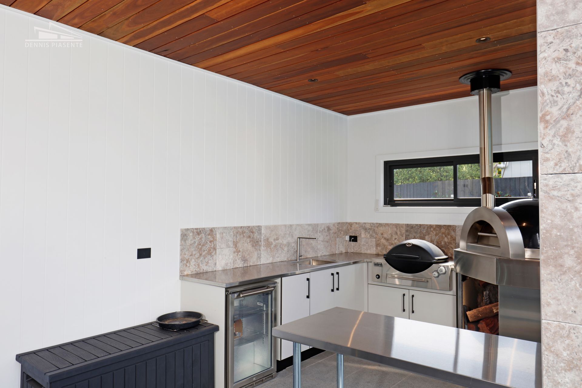 A kitchen with a stainless steel counter top and a pizza oven.