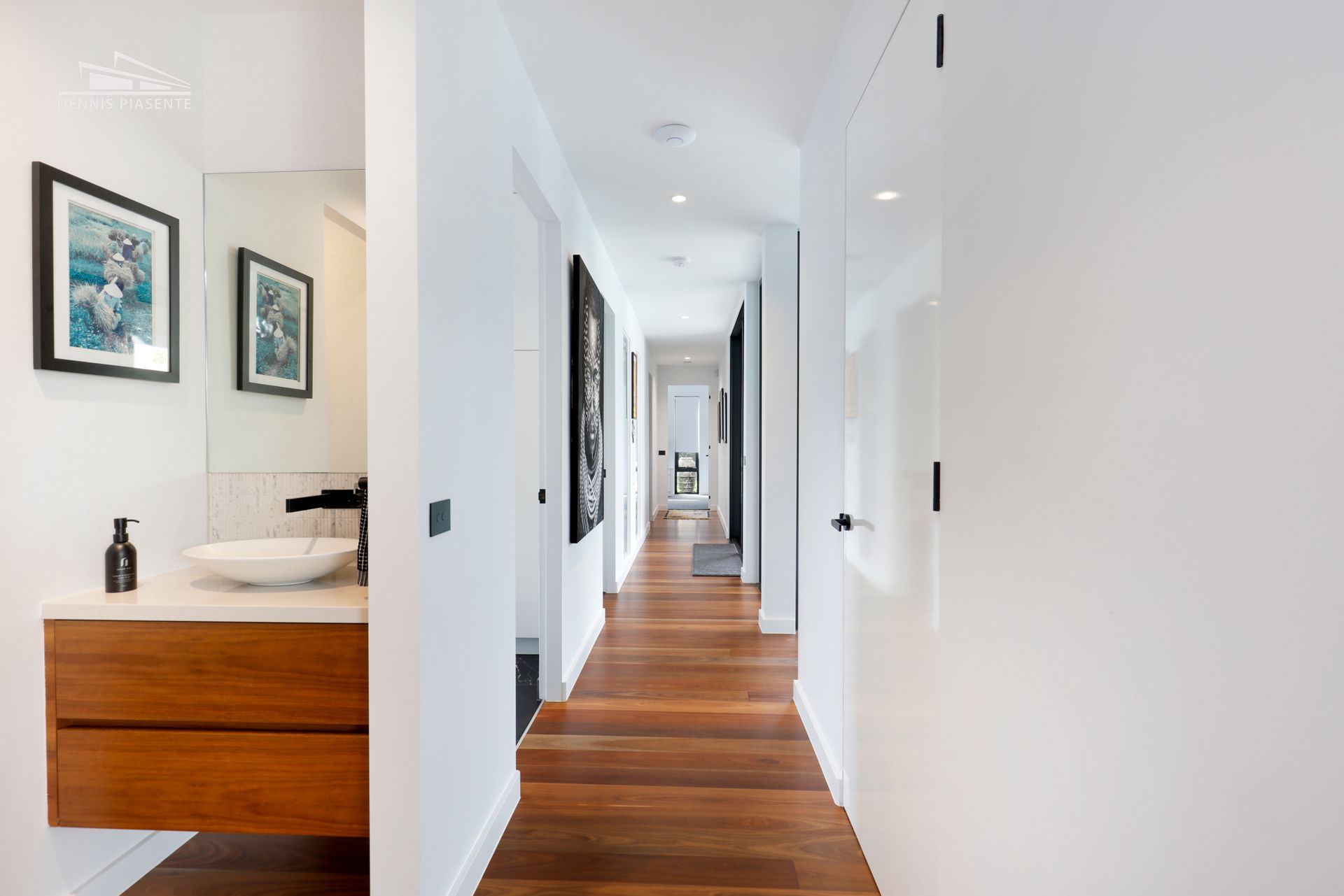 A long hallway leading to a bathroom and a sink.