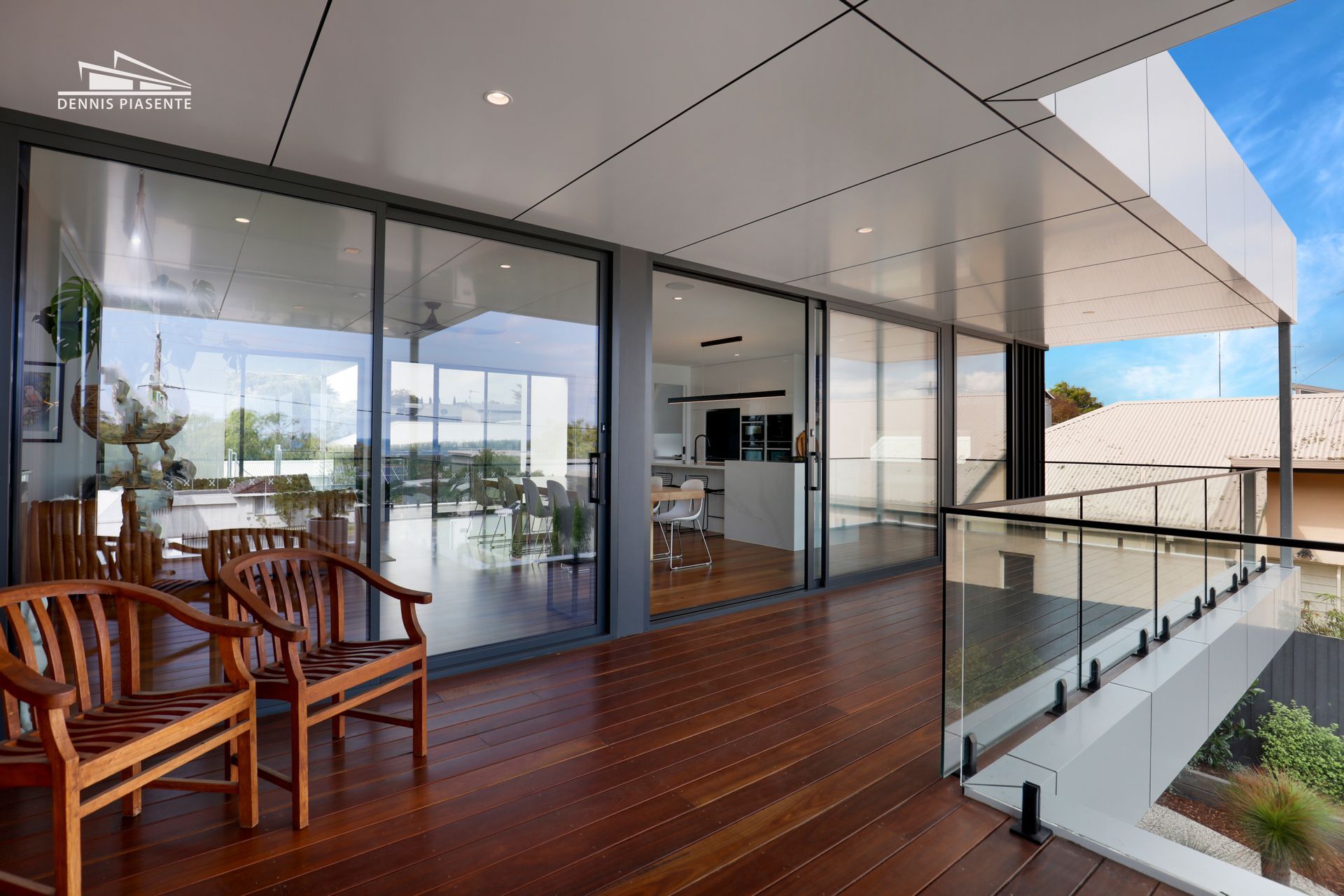 A large balcony with sliding glass doors and wooden chairs.