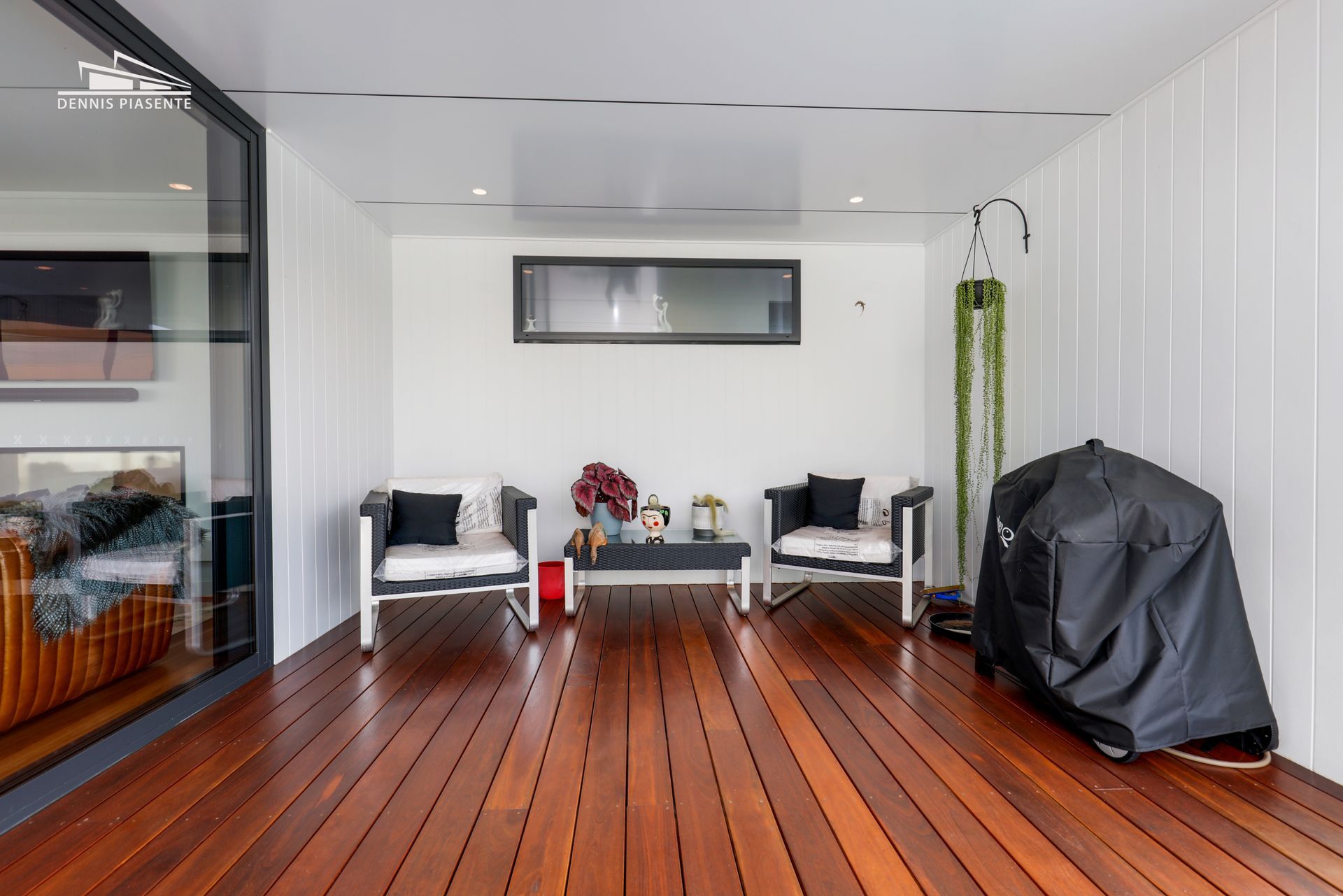 A living room with a wooden floor , chairs , a table and a grill.