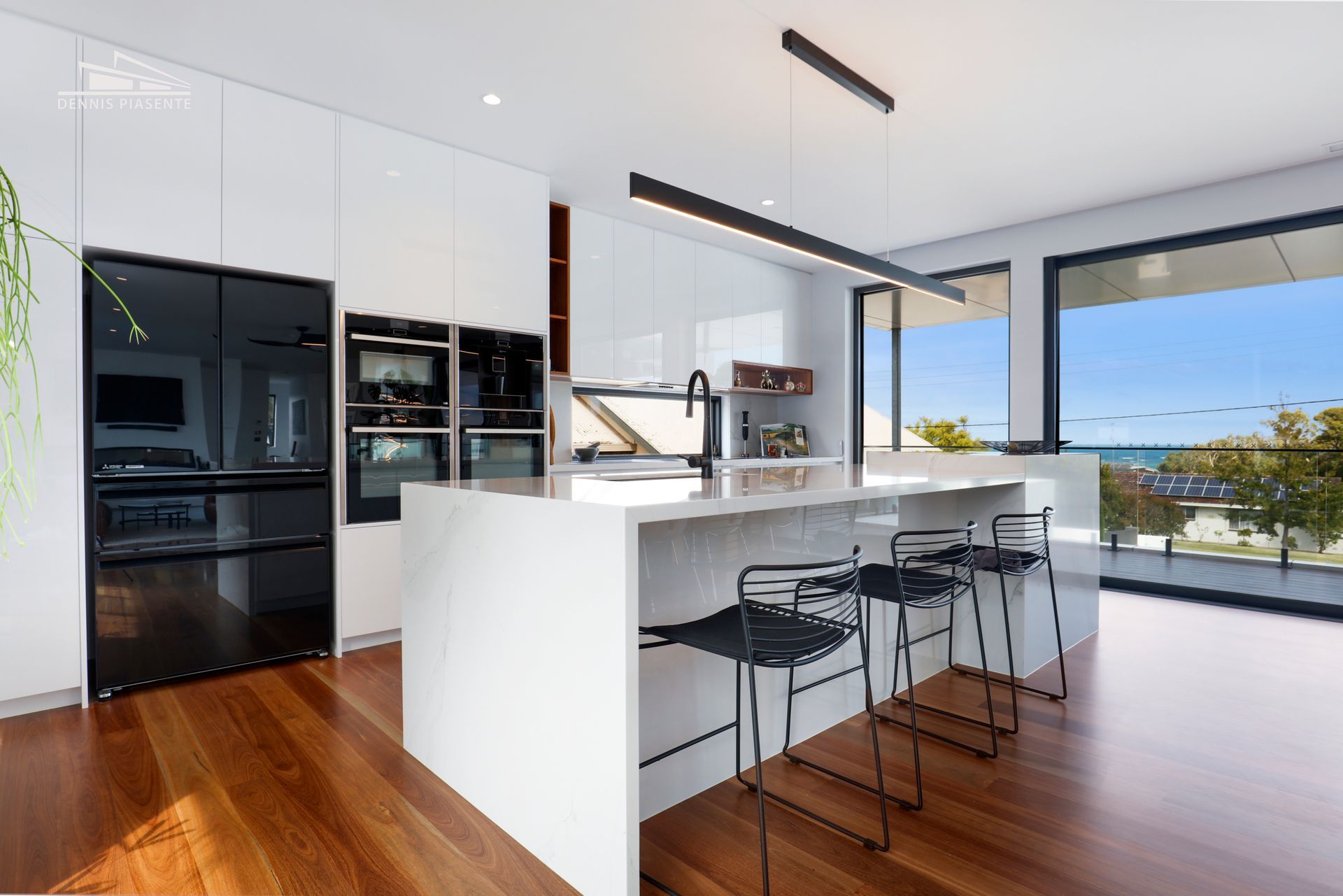 A kitchen with white cabinets and black appliances and a large island.