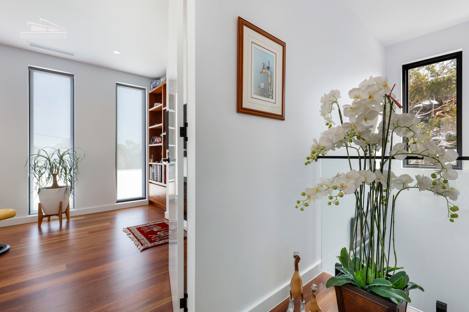 A hallway in a house with wooden floors and a picture on the wall.