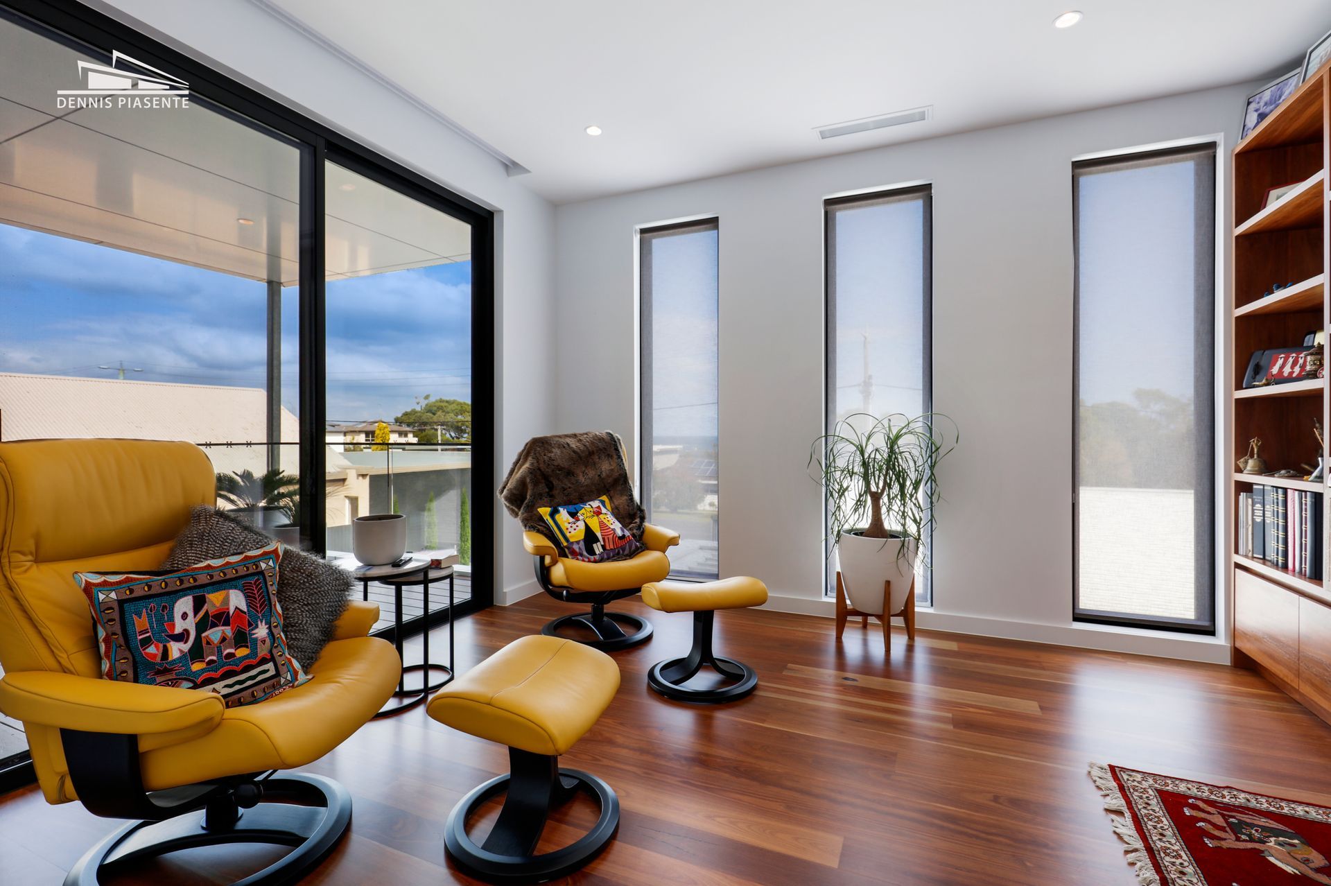 A living room with a yellow chair and ottoman and lots of windows.