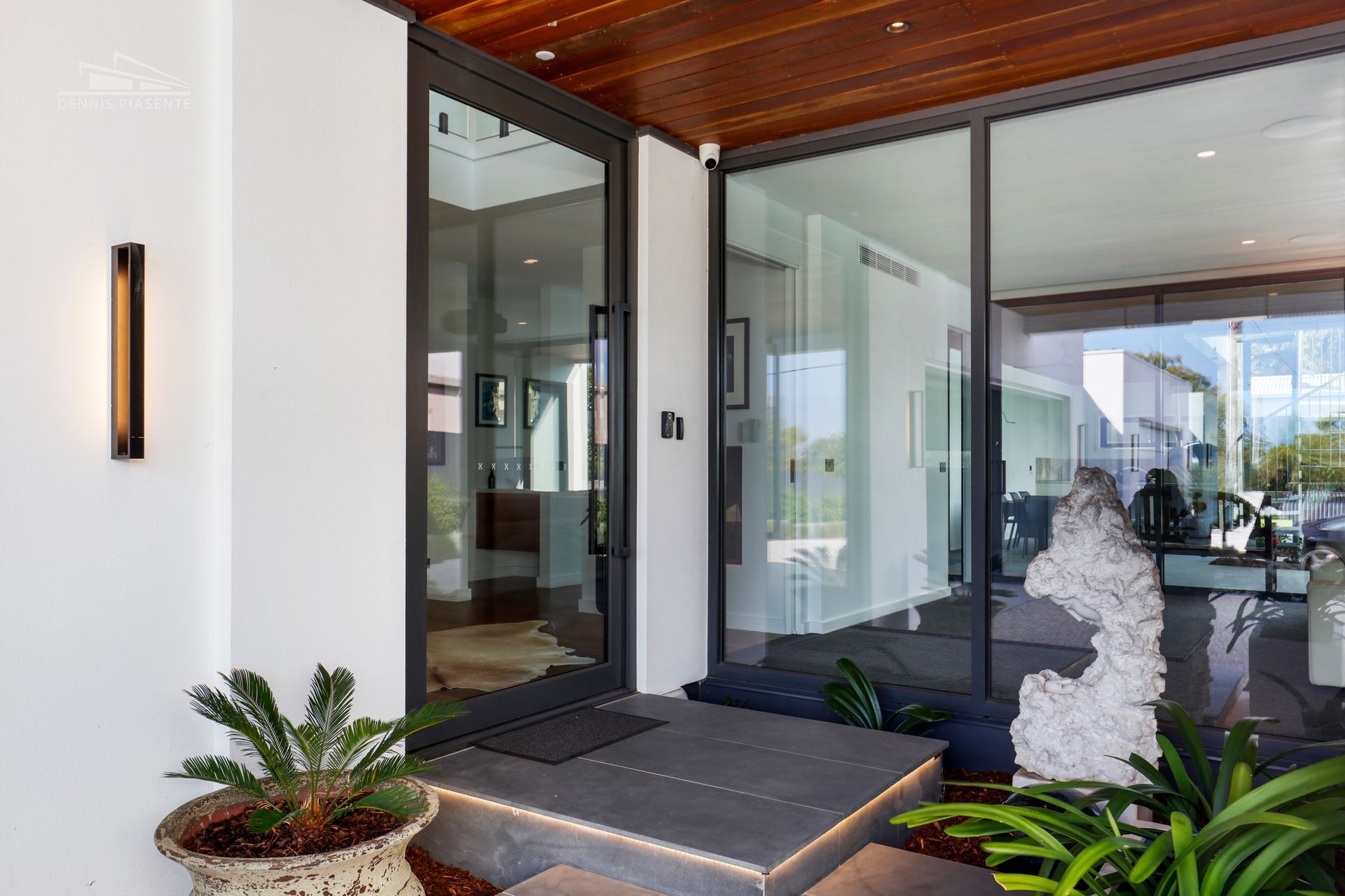 A modern house with a large glass door and a potted plant in front of it.
