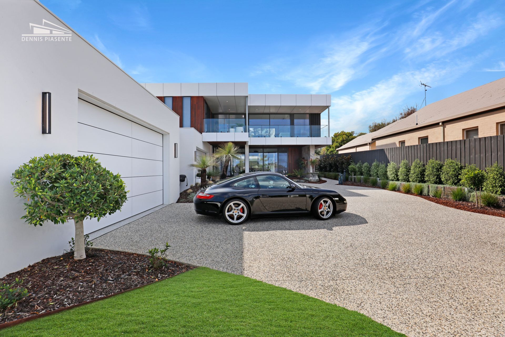 A black car is parked in front of a large white house.
