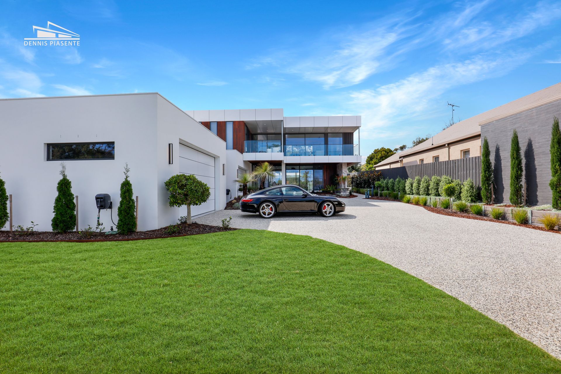 A black car is parked in front of a large white house.