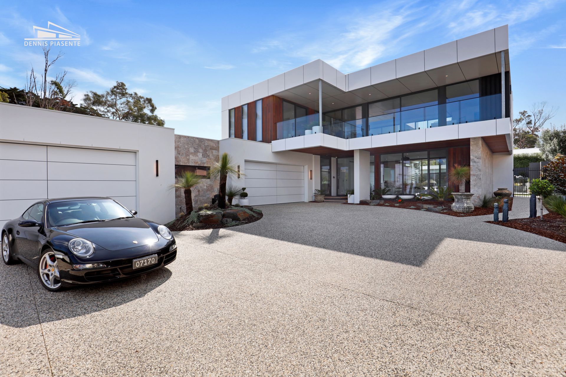 A black car is parked in front of a large house
