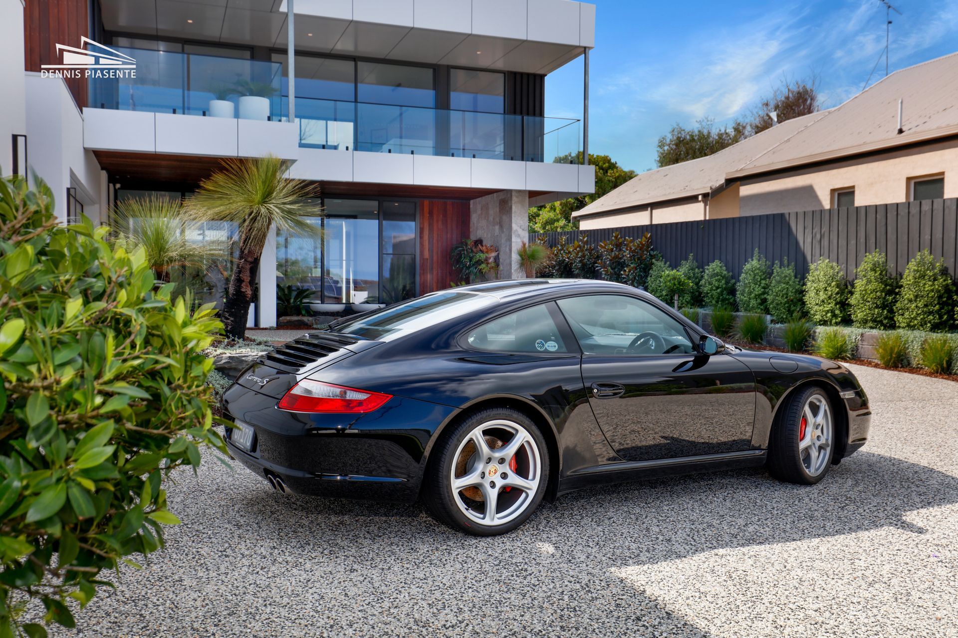 A black sports car is parked in front of a house.