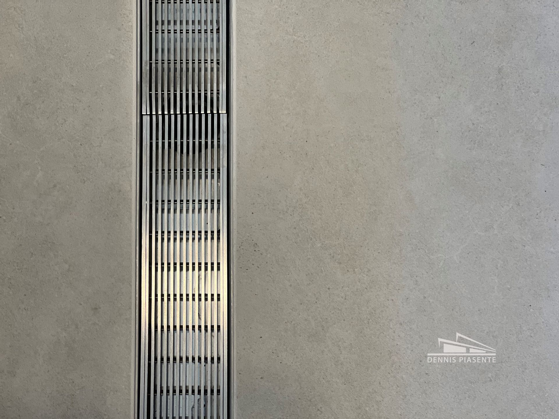 A close up of a gray wall with a metal grate on it.