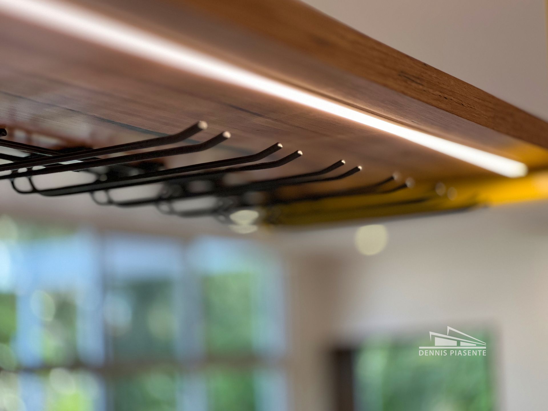 A wine rack is hanging from the ceiling in a kitchen.