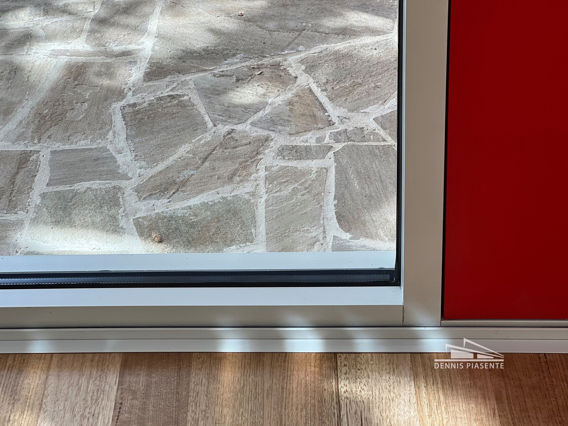 A close up of a window with a red door in the background