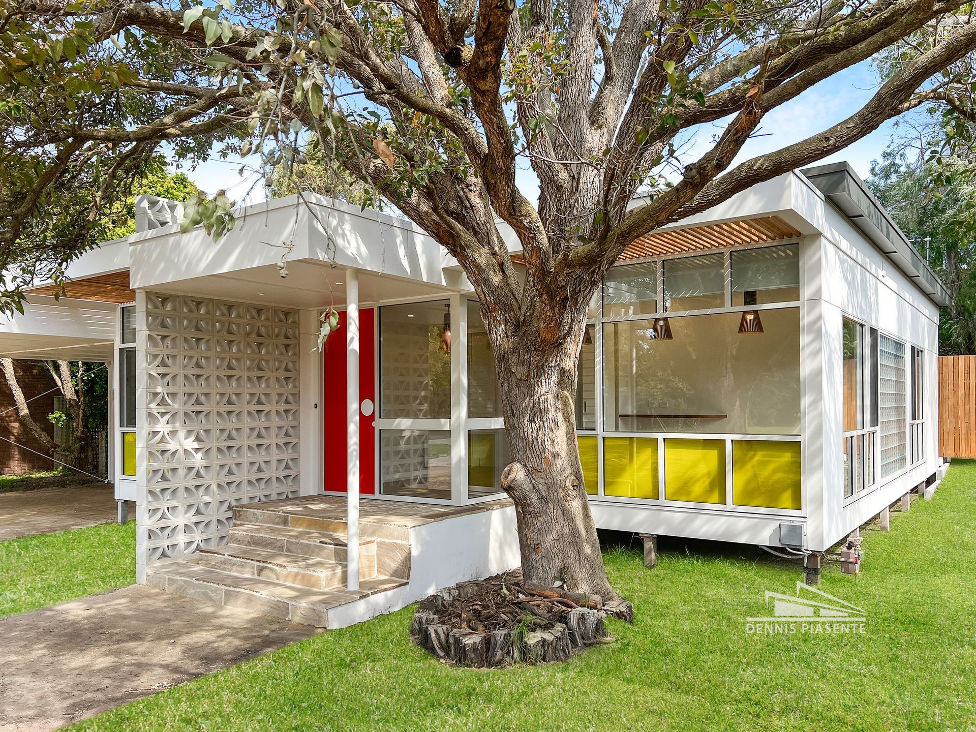 A small white house with a tree in front of it.