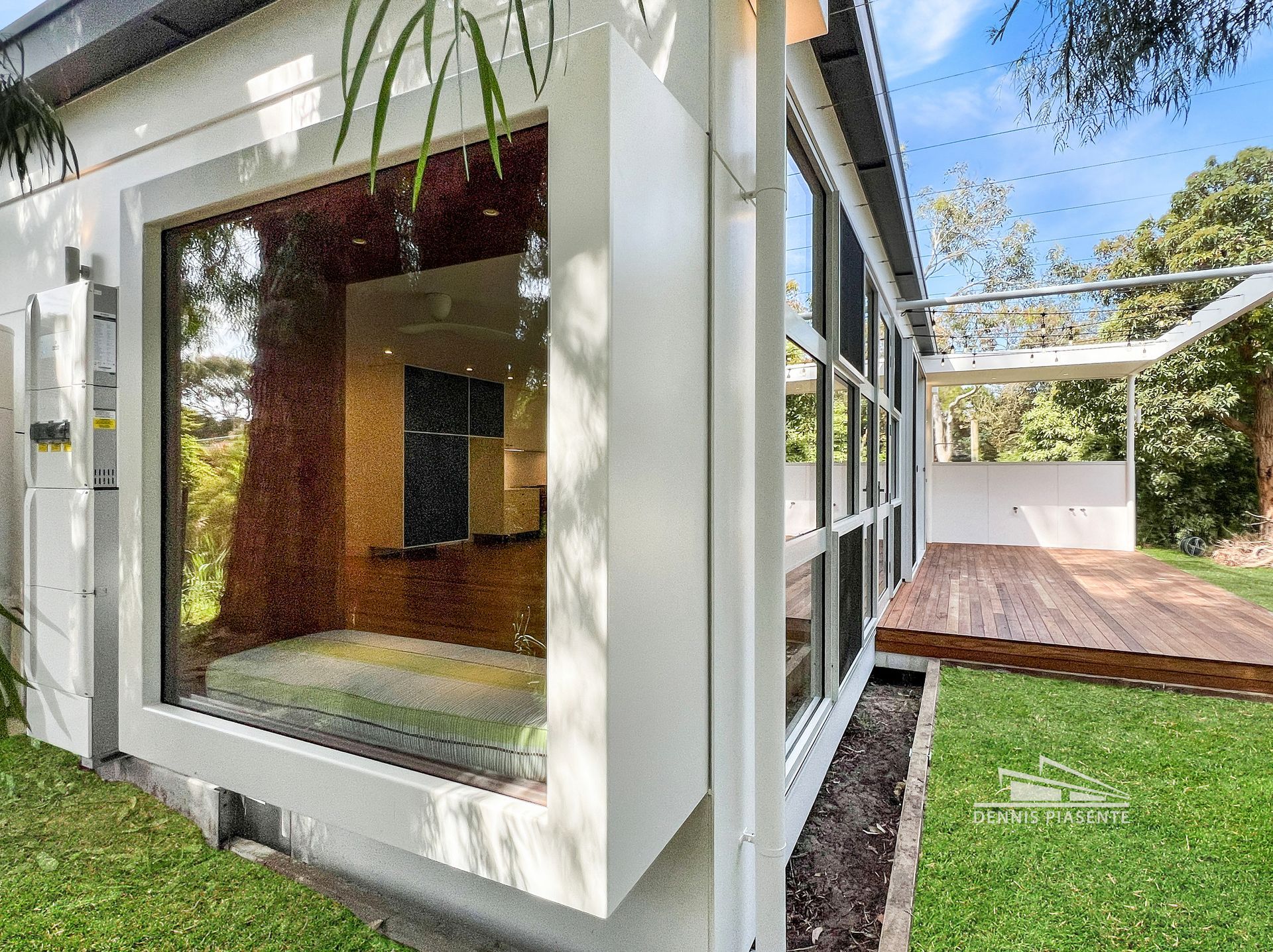 A white house with a large window and a wooden deck.