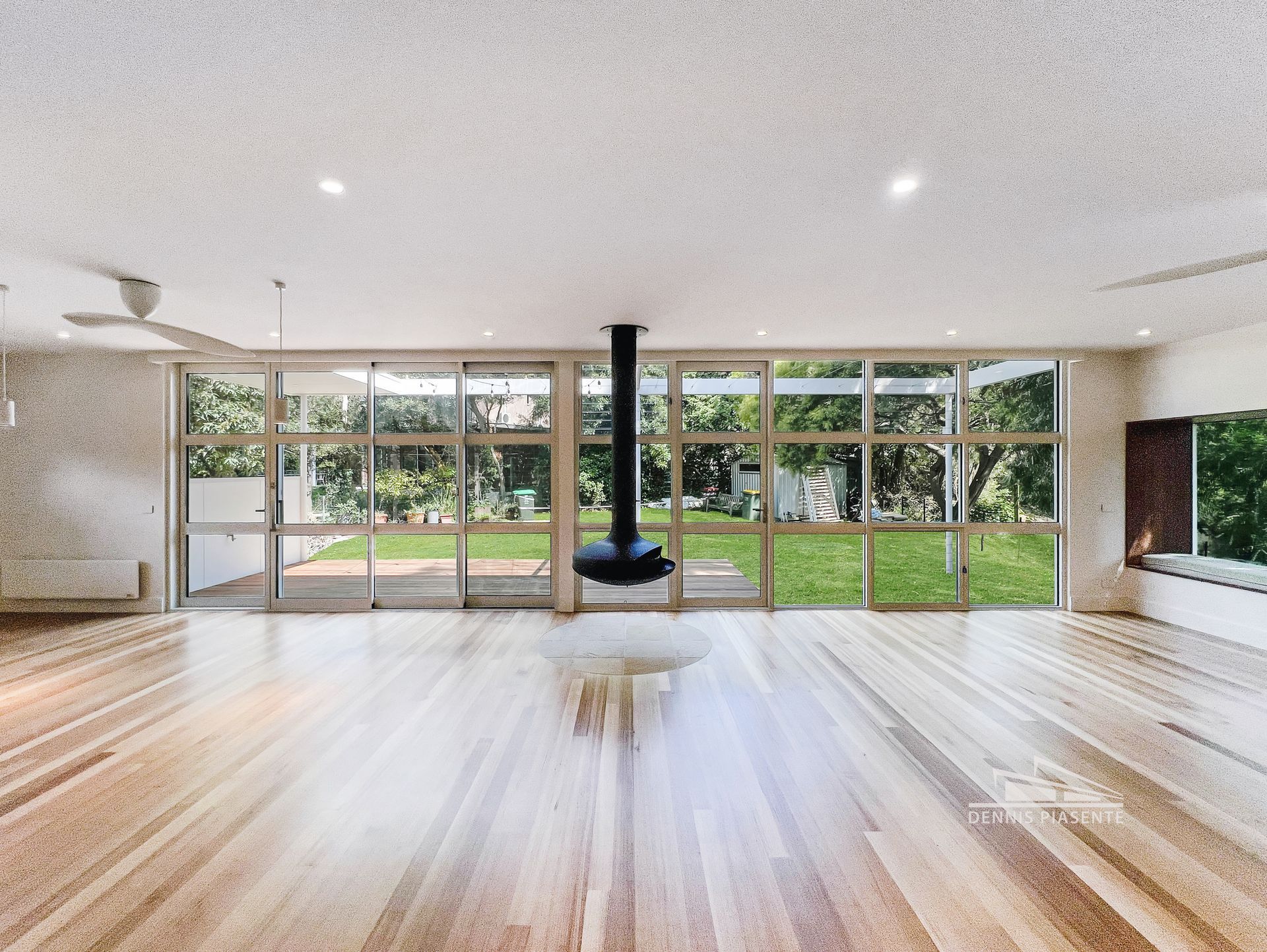 A large empty room with hardwood floors and lots of windows.