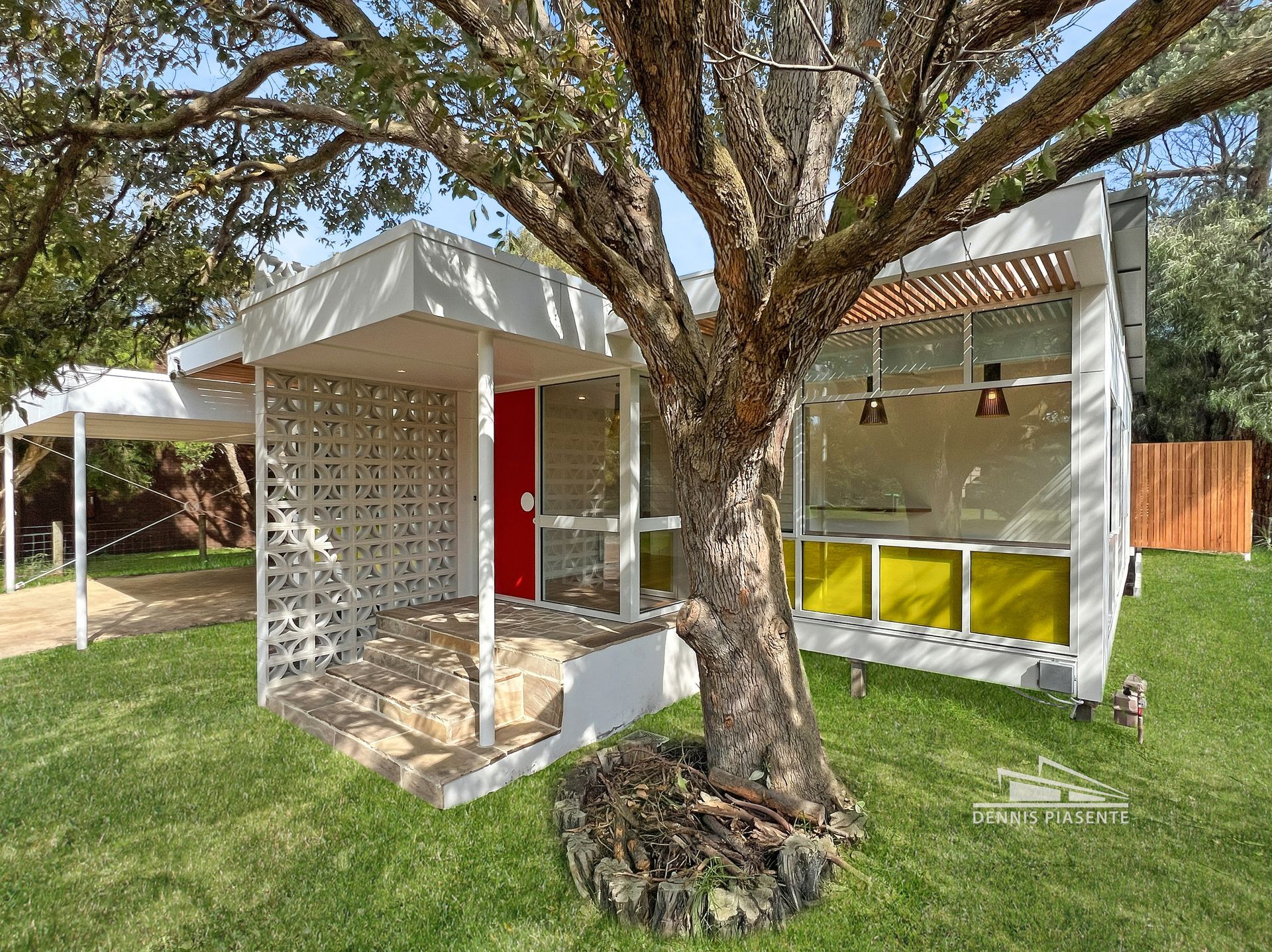 A small white house with a tree in front of it.