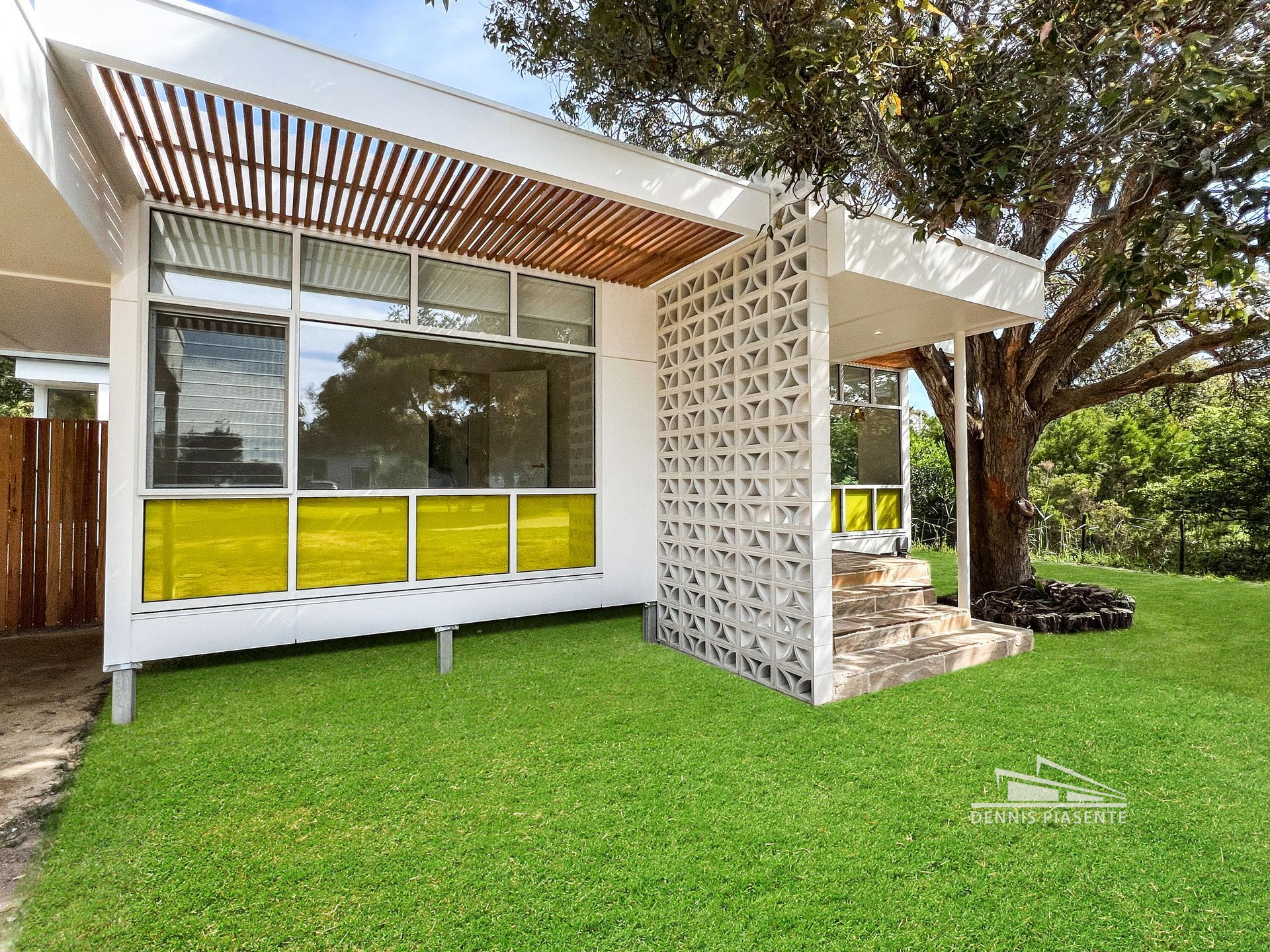 A small white house with yellow windows is sitting on top of a lush green lawn.