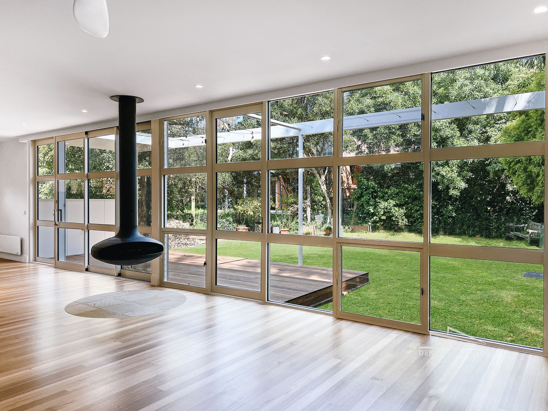 An empty living room with lots of windows and a fireplace