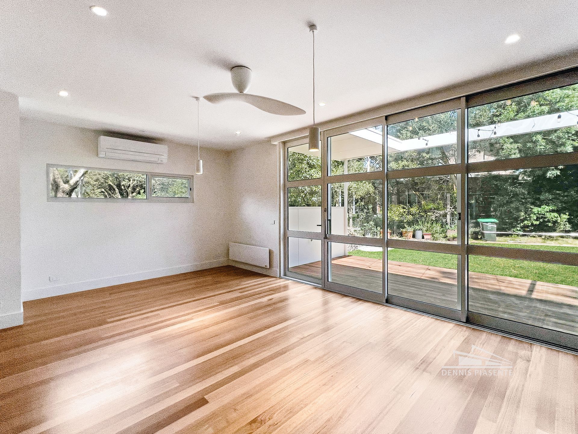 An empty living room with hardwood floors and a ceiling fan.