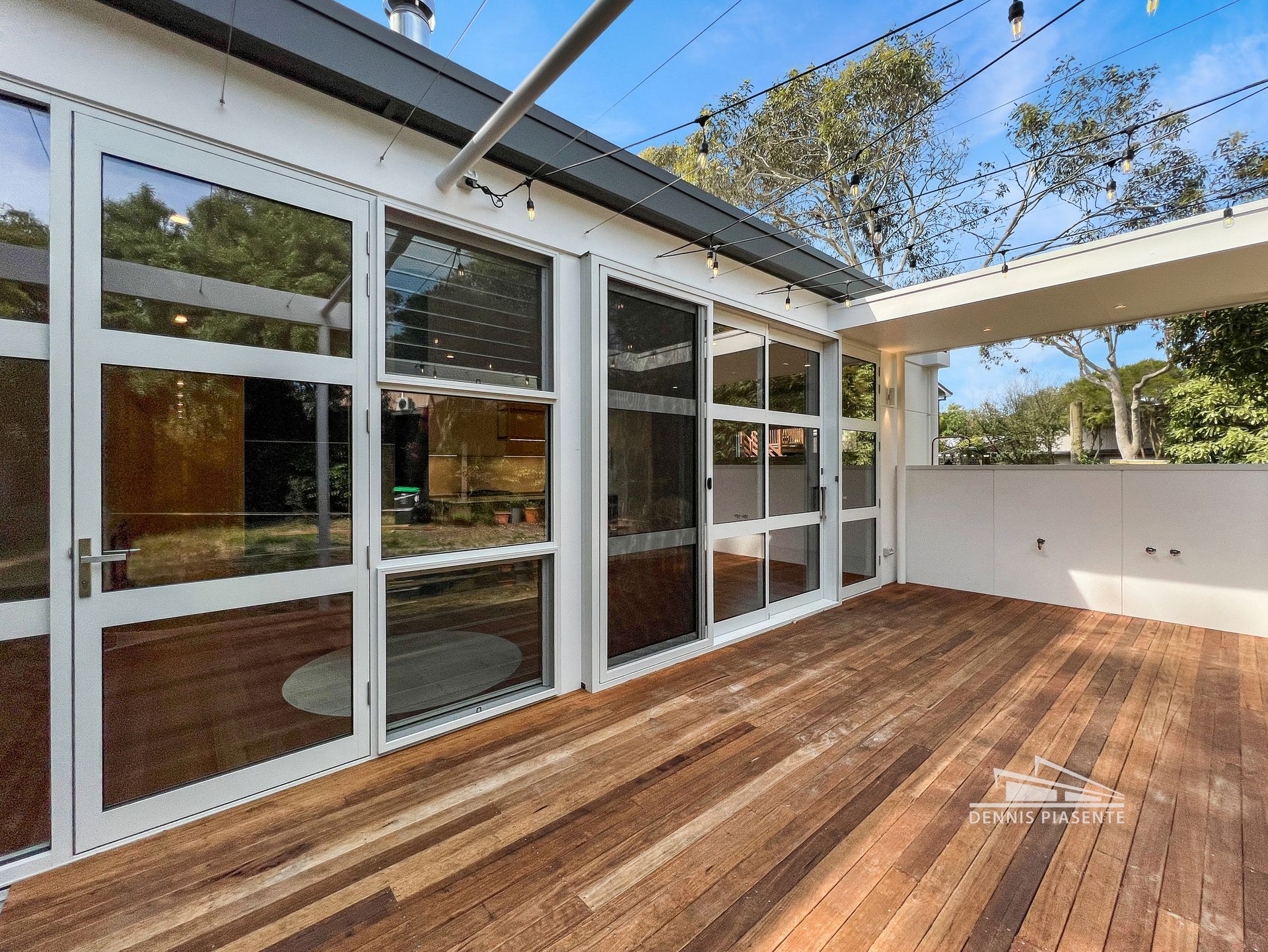 There is a wooden deck in front of a house with a lot of windows.