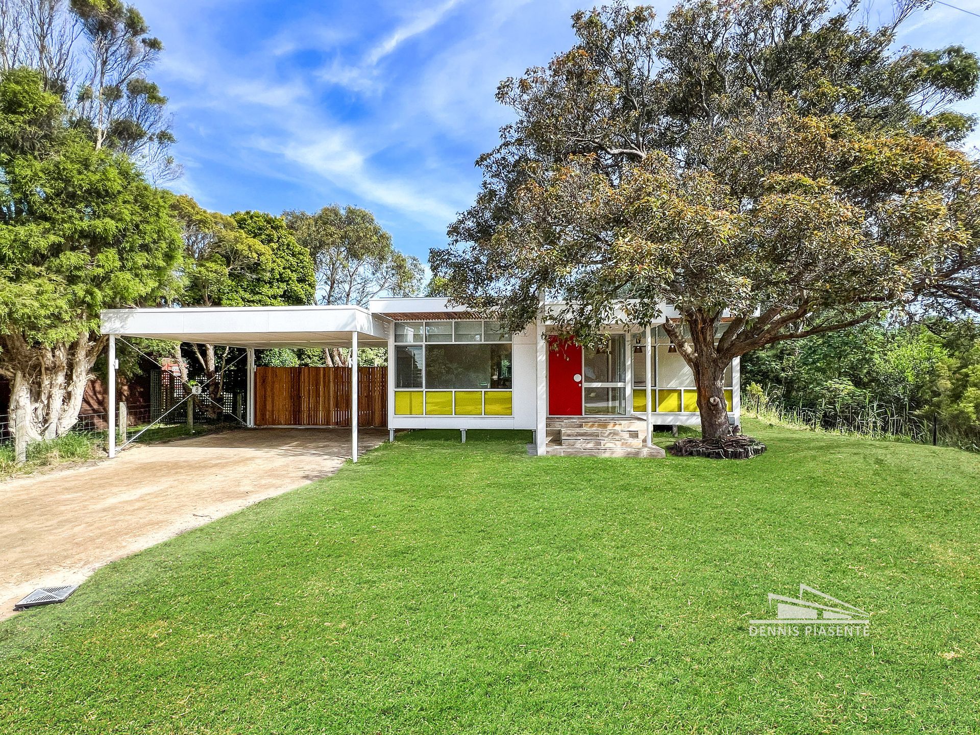 A white house with a red door is sitting on top of a lush green hill.