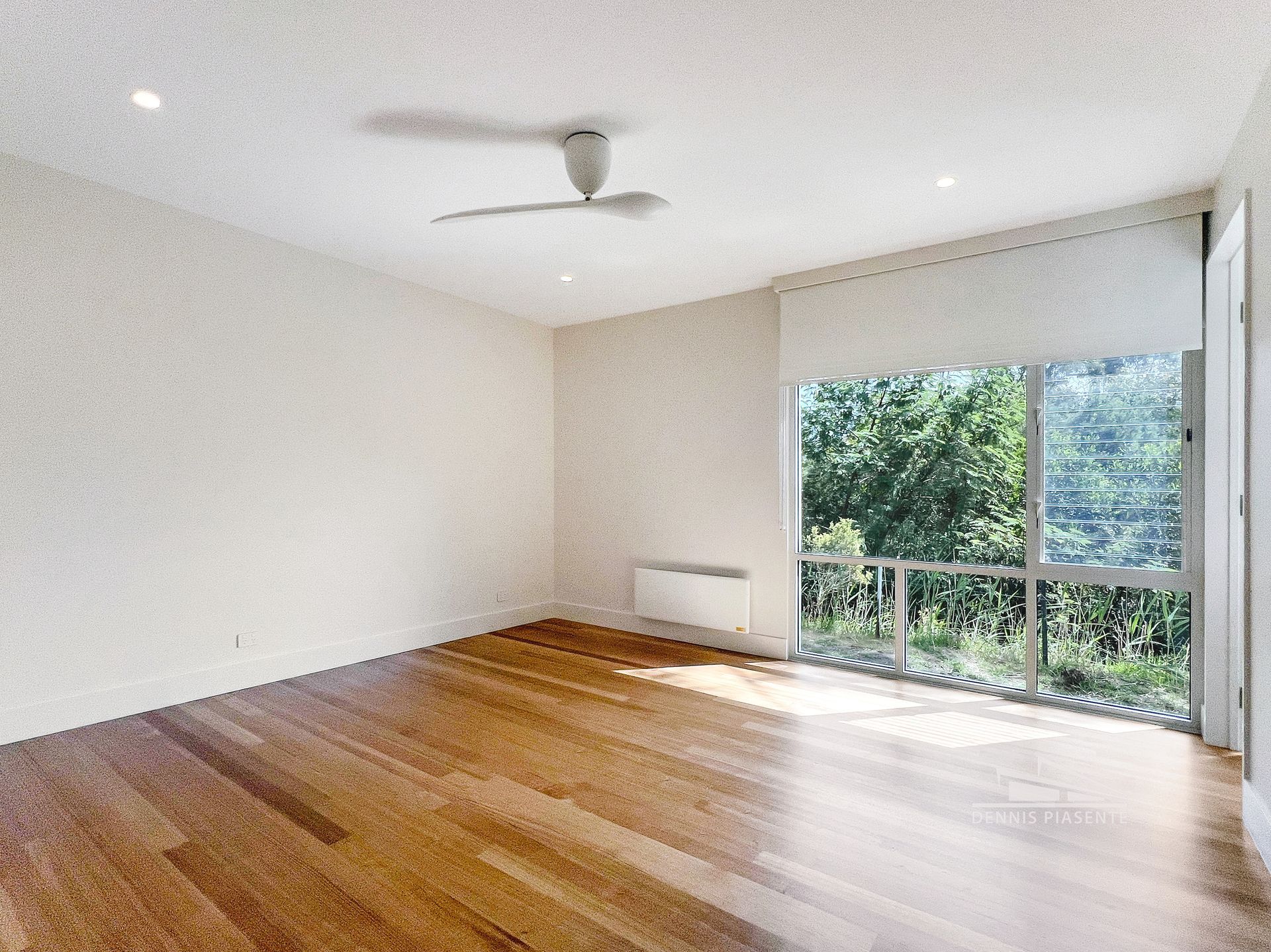 An empty room with hardwood floors and a ceiling fan