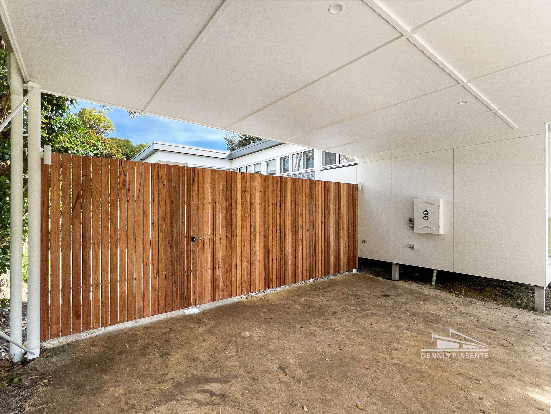 A carport with a wooden fence and a white roof.