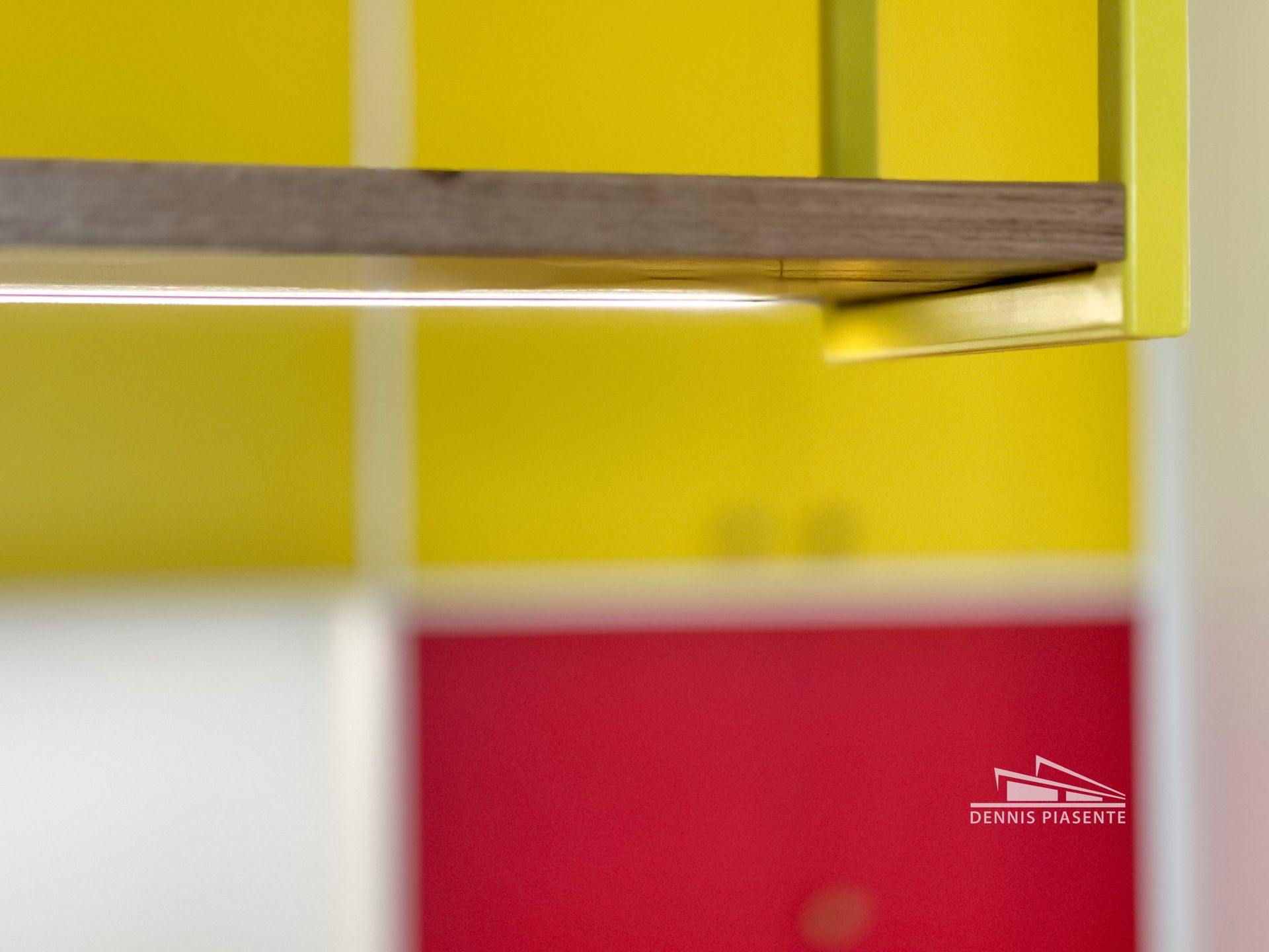 A red and yellow kitchen with a wooden shelf hanging from the ceiling