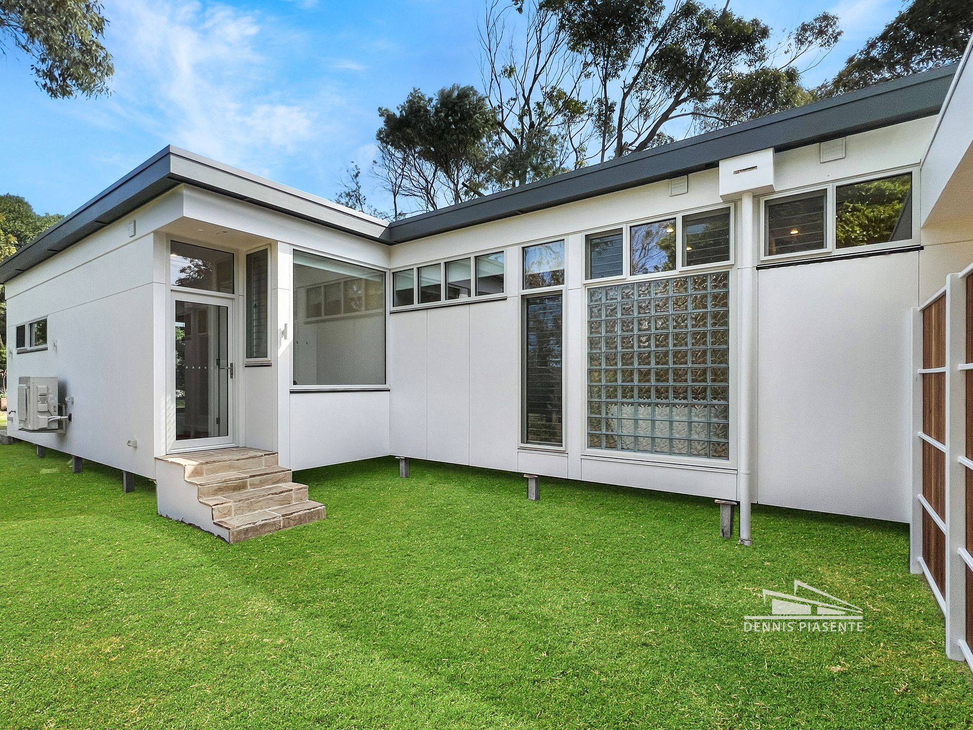 A white house with a lot of windows is sitting on top of a lush green lawn.