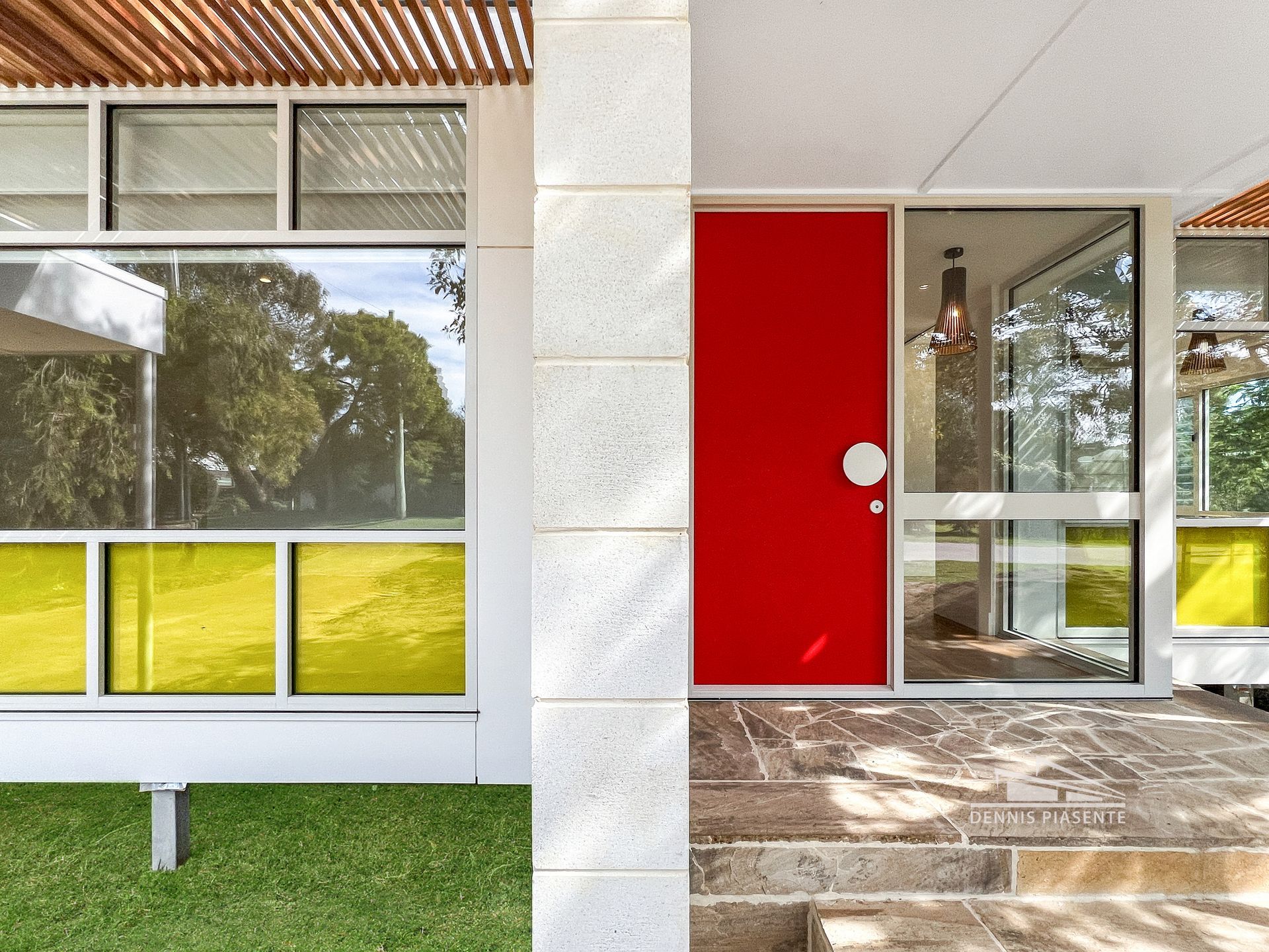 The front of a house with a red door and yellow windows