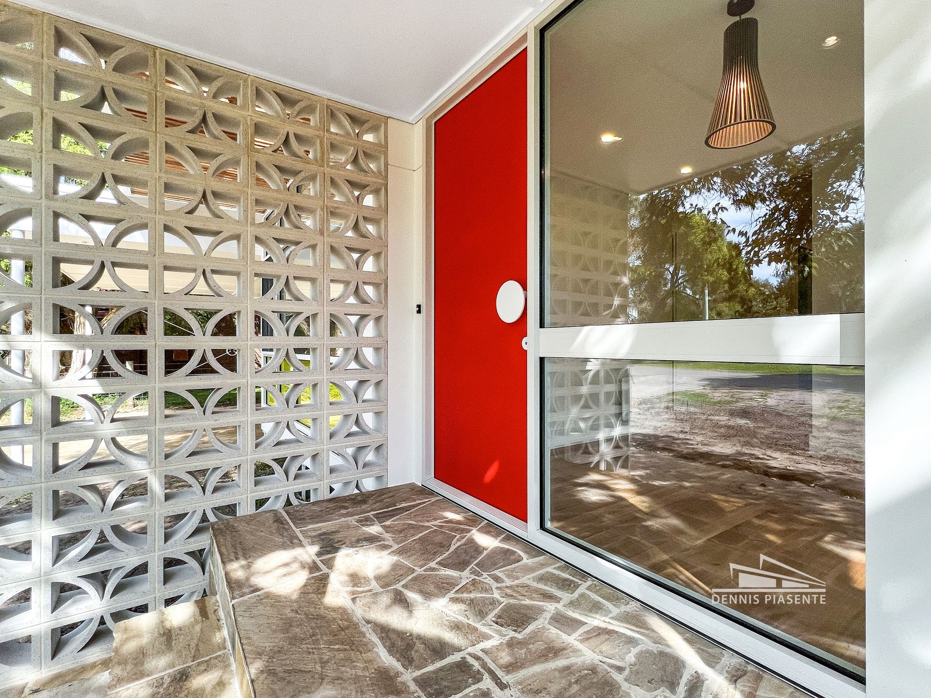 A porch with a red door and a large window.