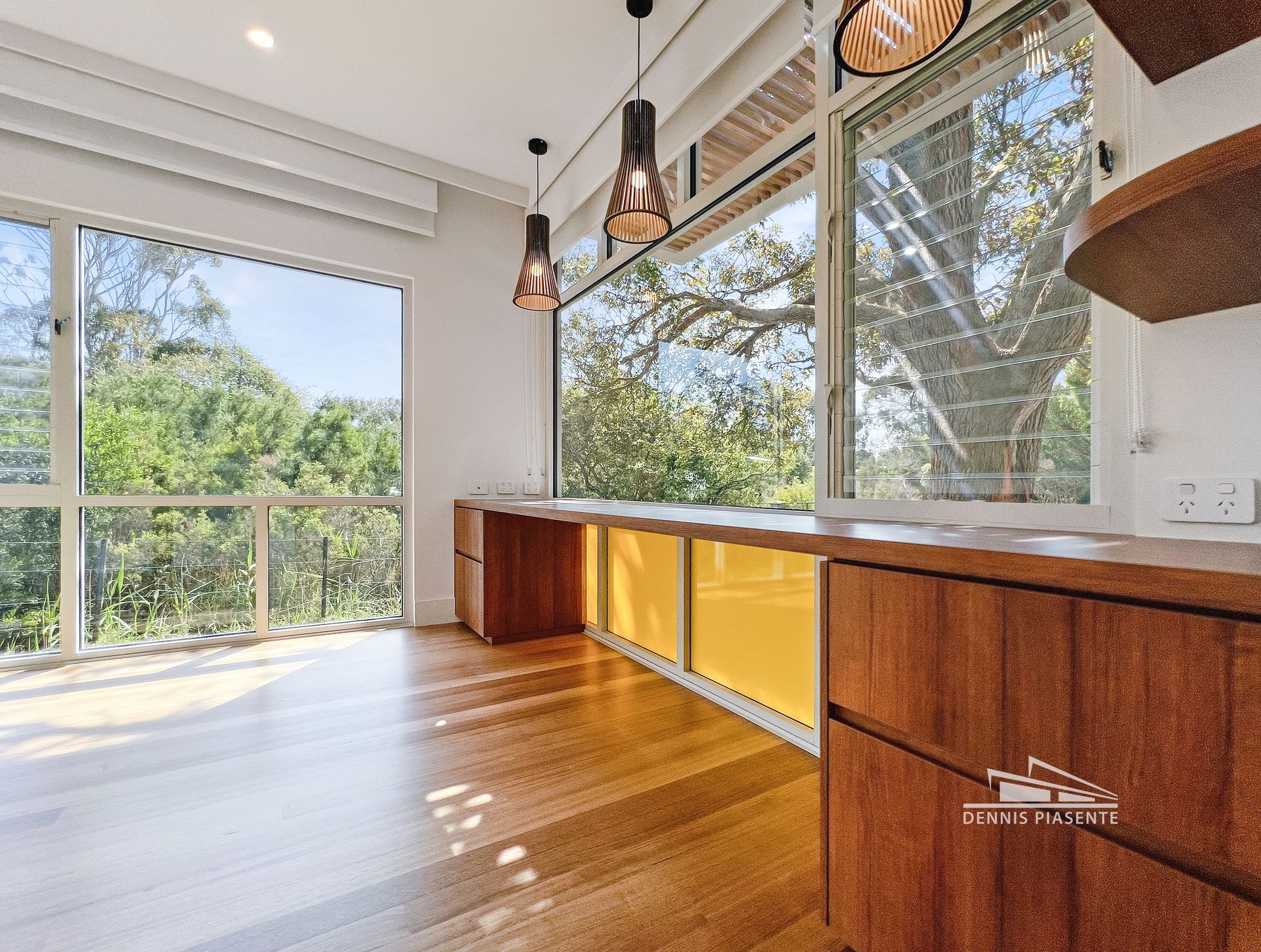 A kitchen with a lot of windows and wooden cabinets.