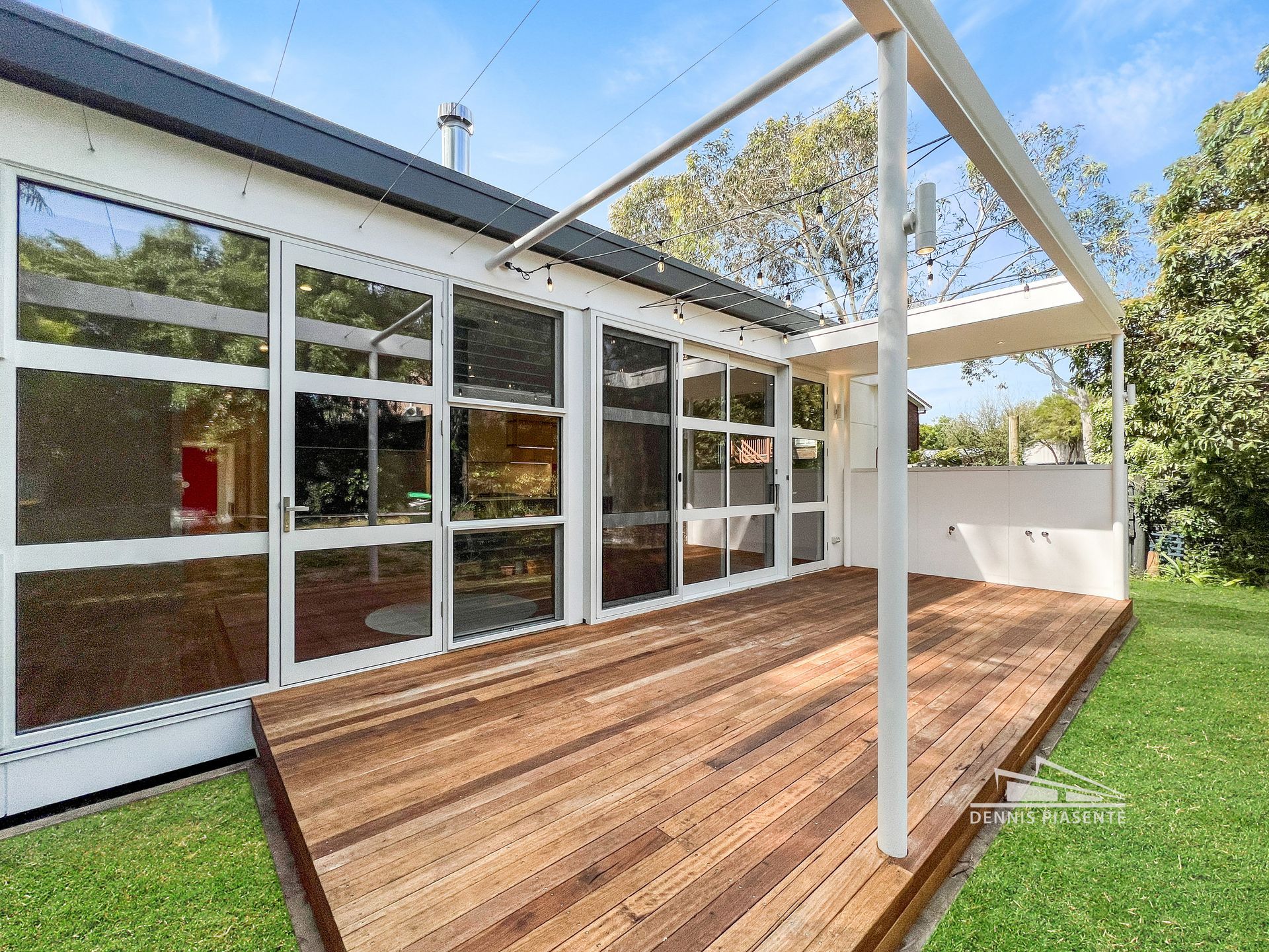 There is a wooden deck in front of a house with a lot of windows.