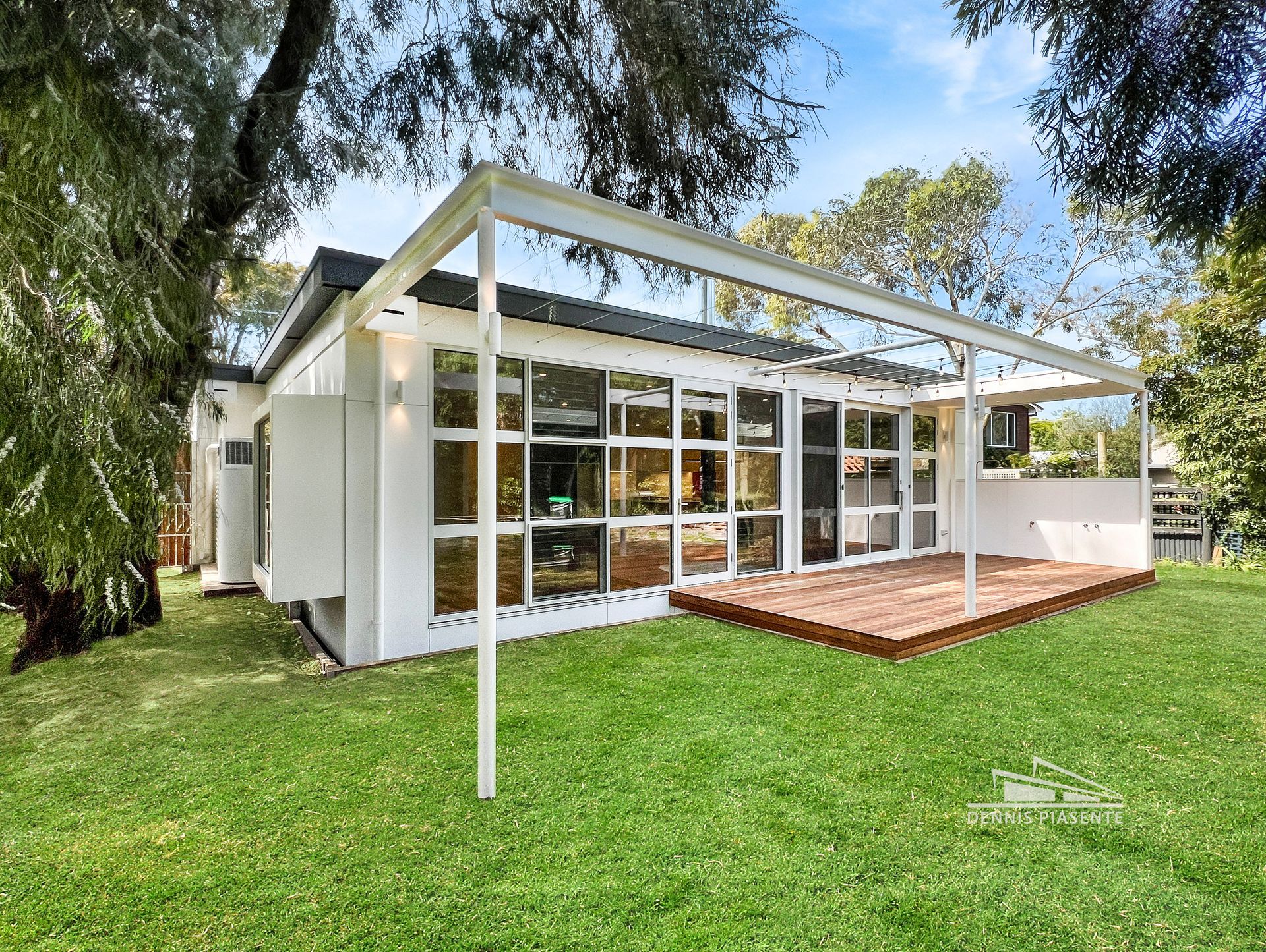 A small white house with a large deck in the backyard.