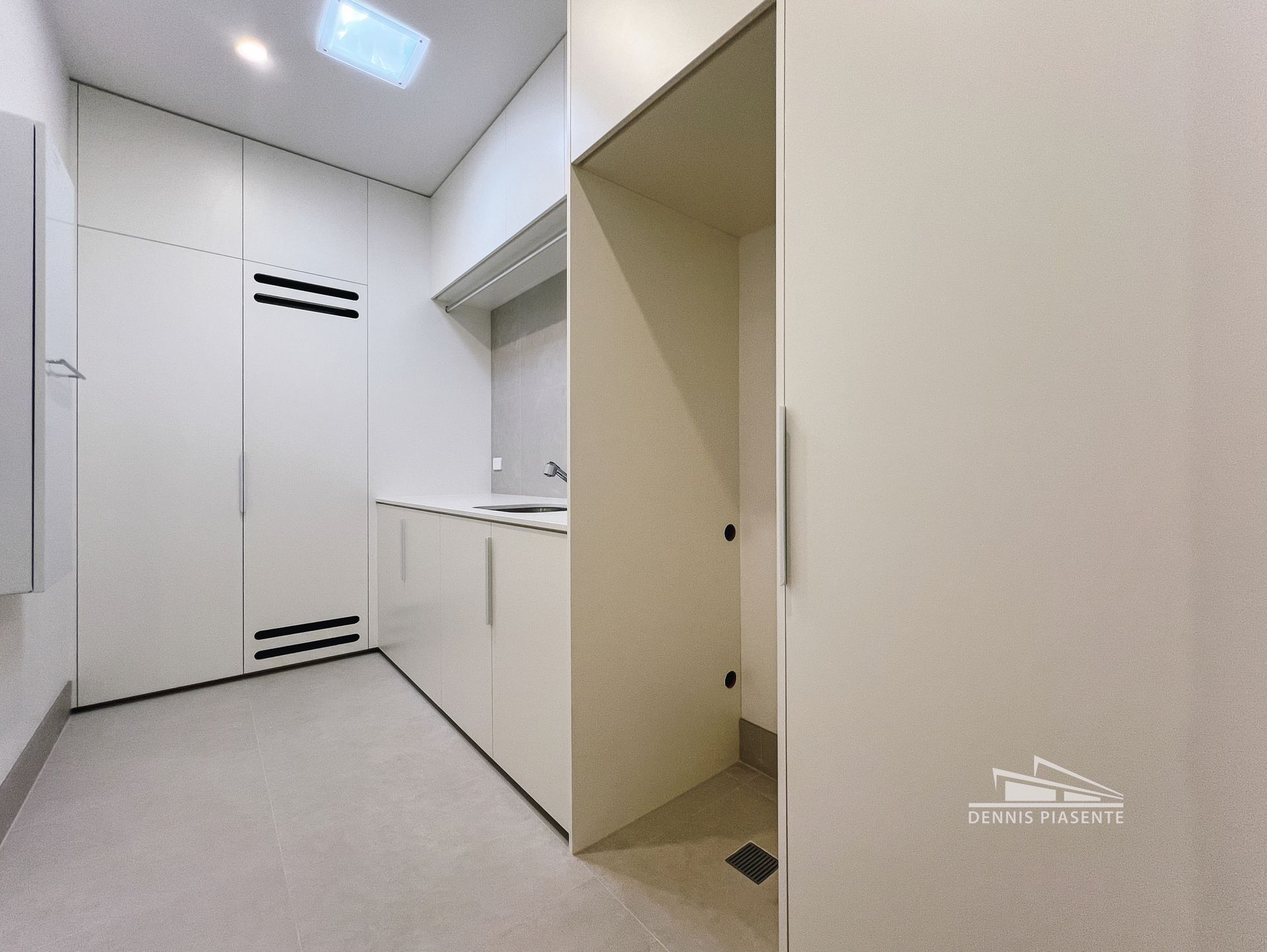 A laundry room with white cabinets and a sink.