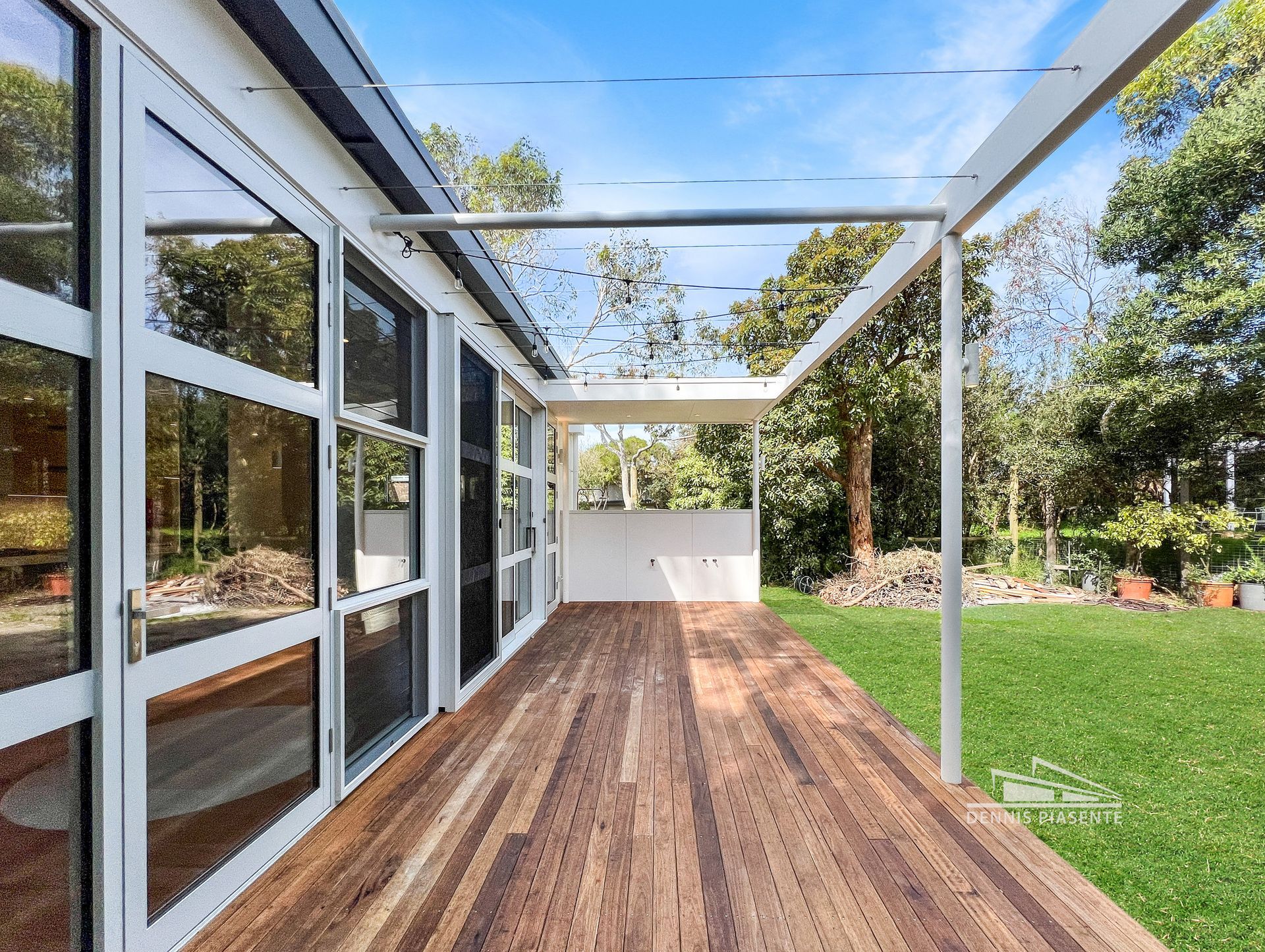 There is a wooden deck in front of a house with a lot of windows.