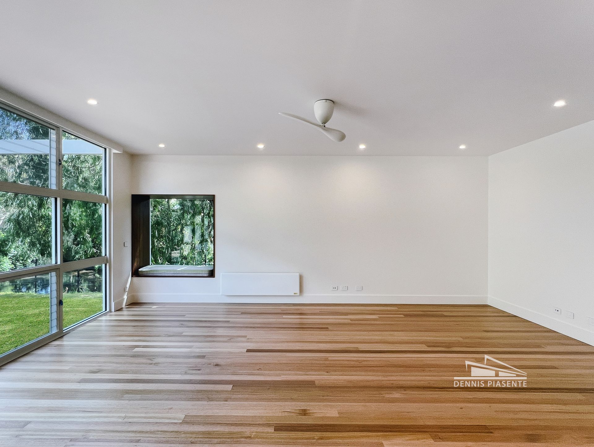 A large empty room with wooden floors and a window.