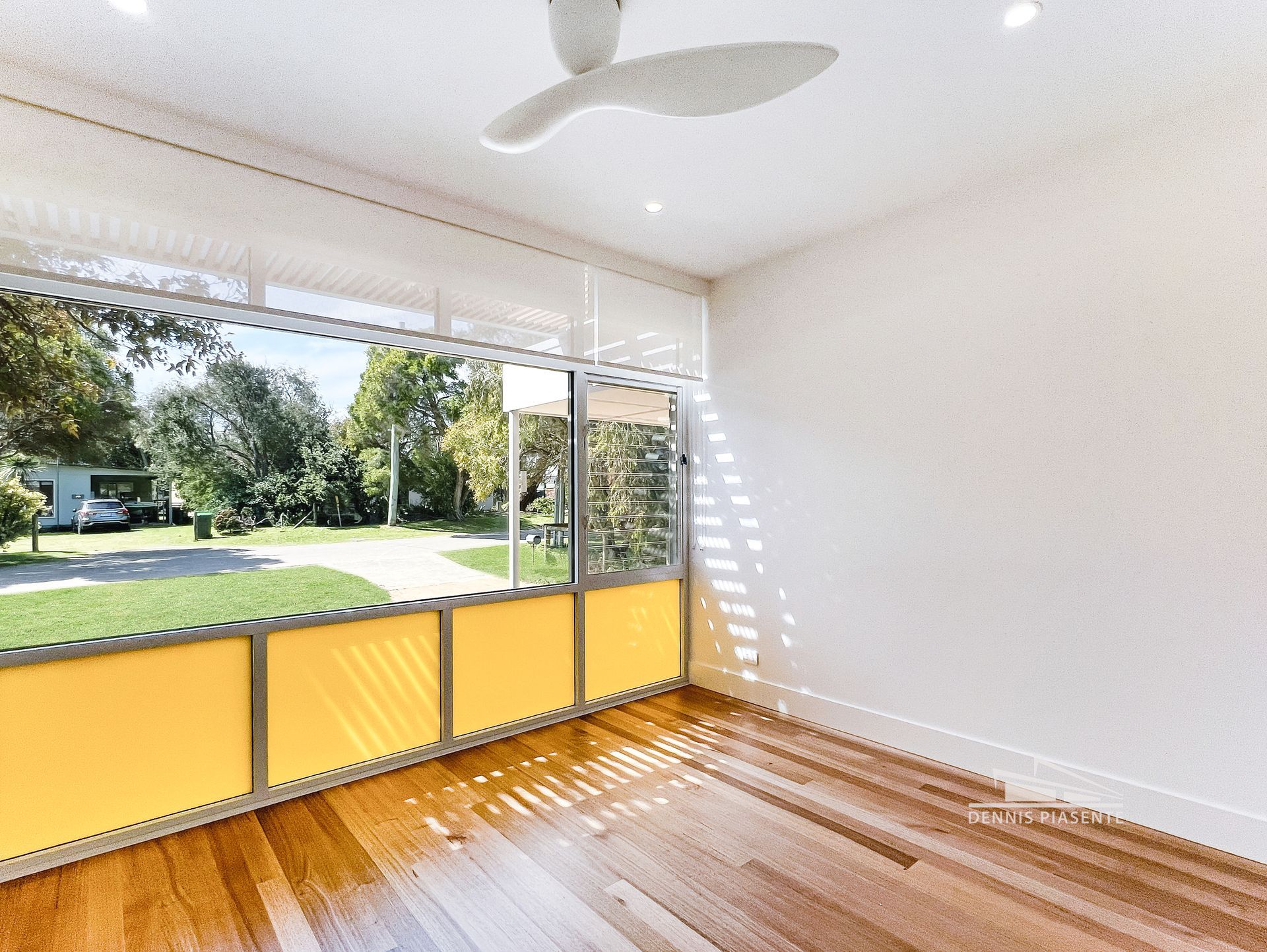An empty room with a ceiling fan and a large window.