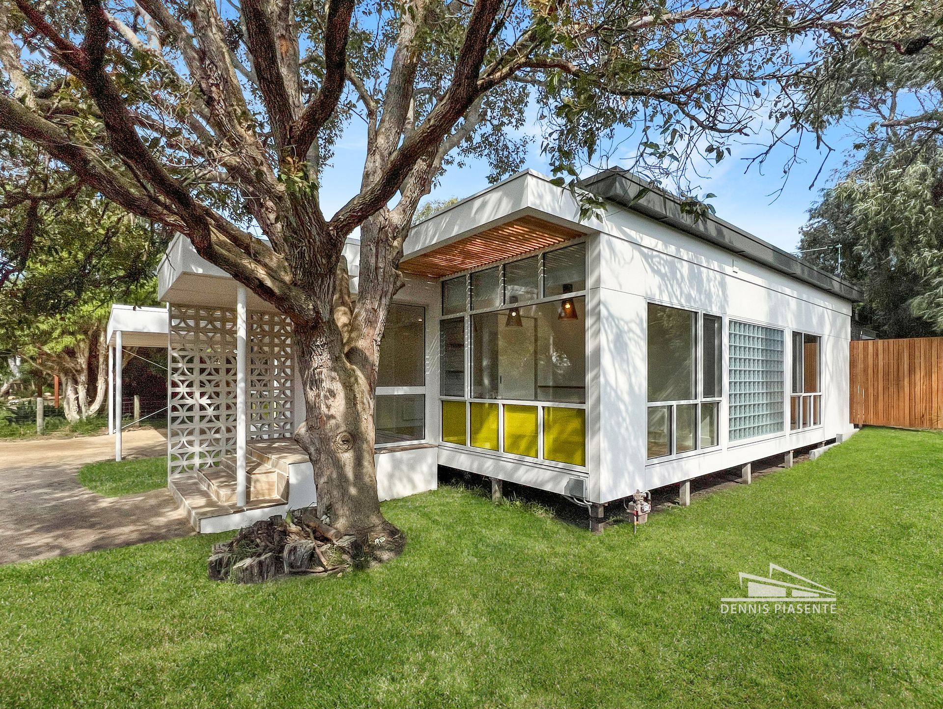 A small white house with a lot of windows and a tree in front of it.
