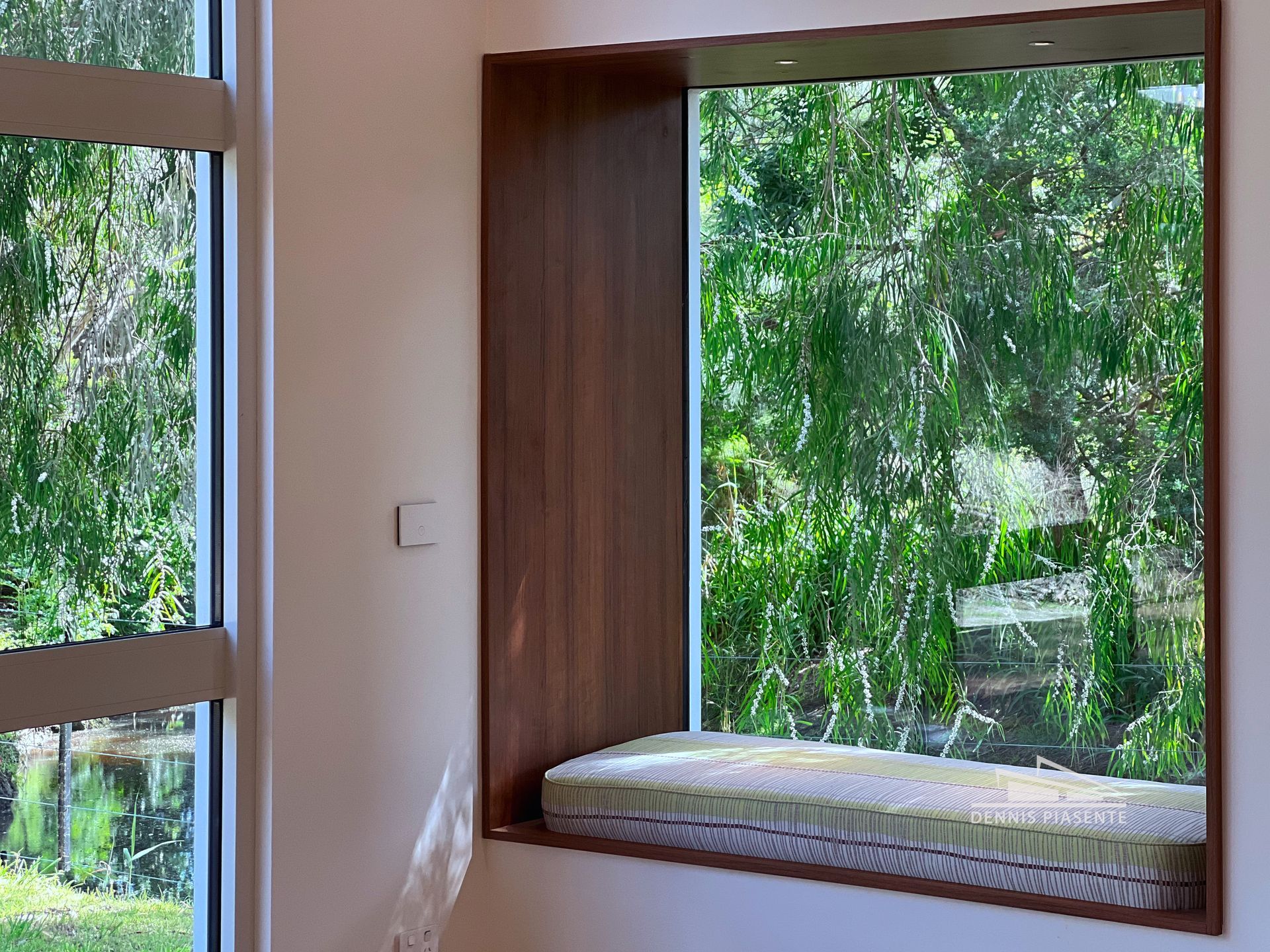A window with a bench in it and a view of trees.