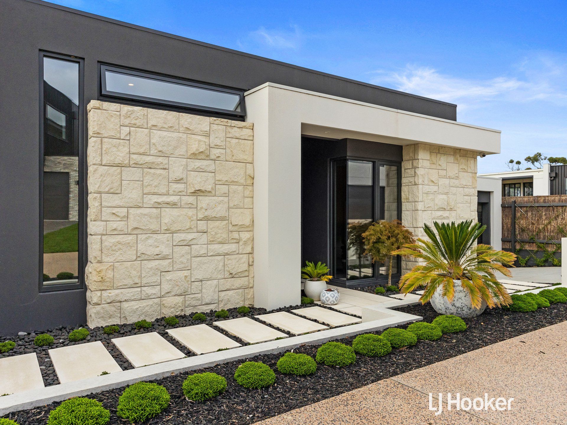 A modern house with a stone wall and a walkway