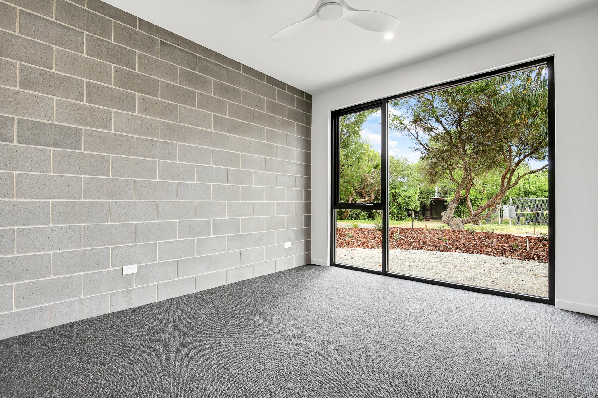 An empty room with a large window and a brick wall.