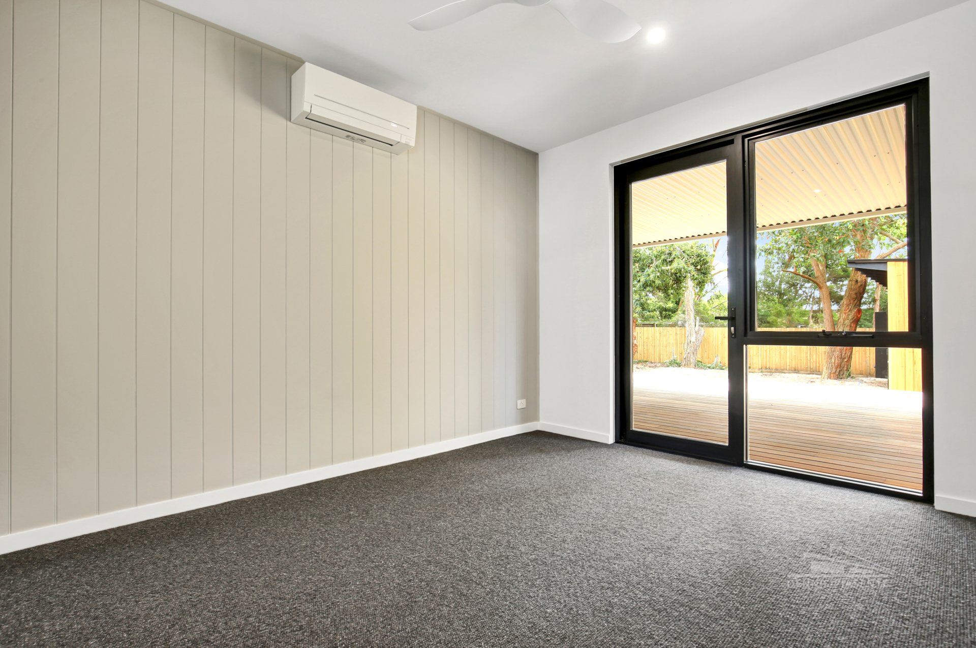 An empty room with a sliding glass door and a ceiling fan.