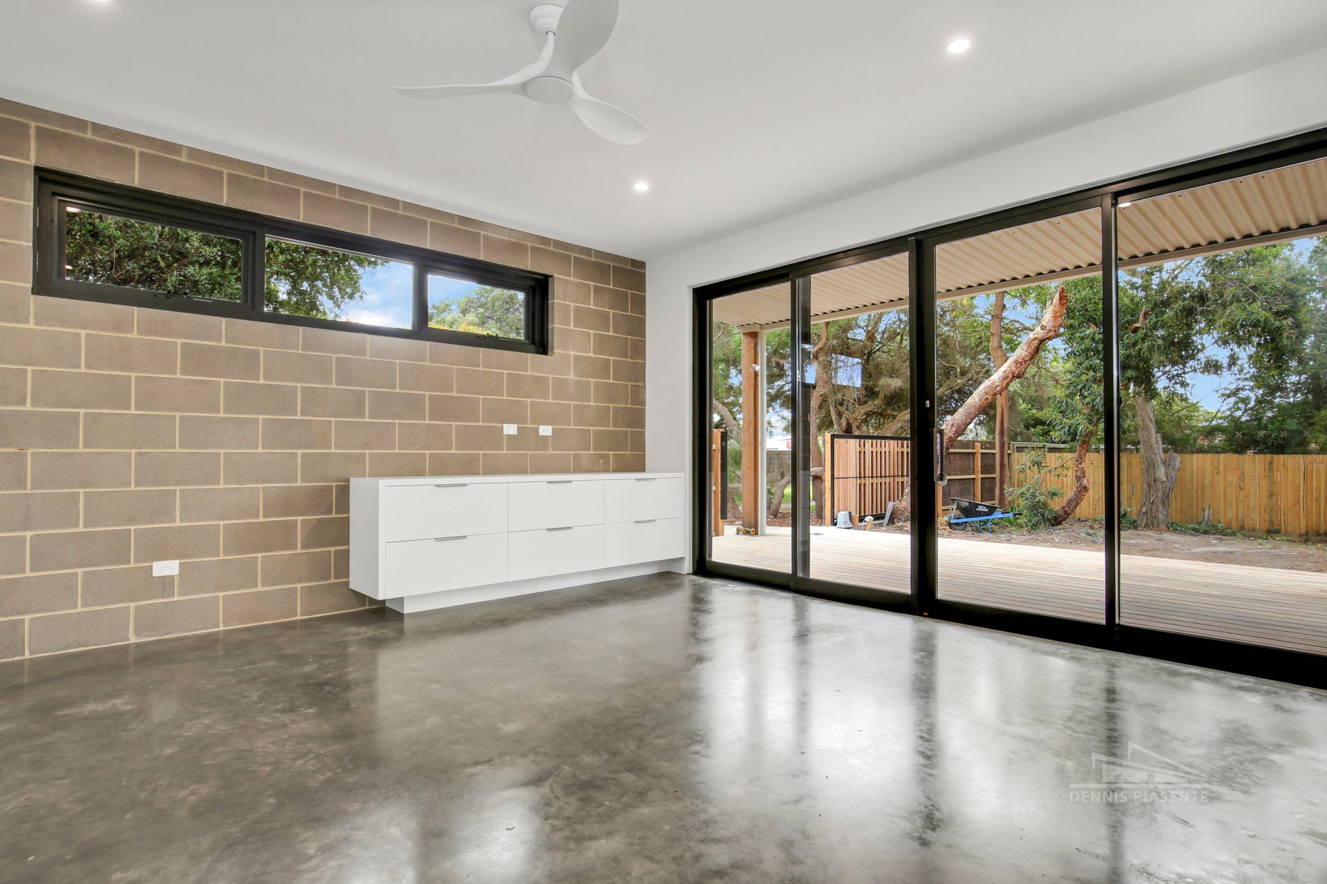 An empty living room with sliding glass doors and a ceiling fan.