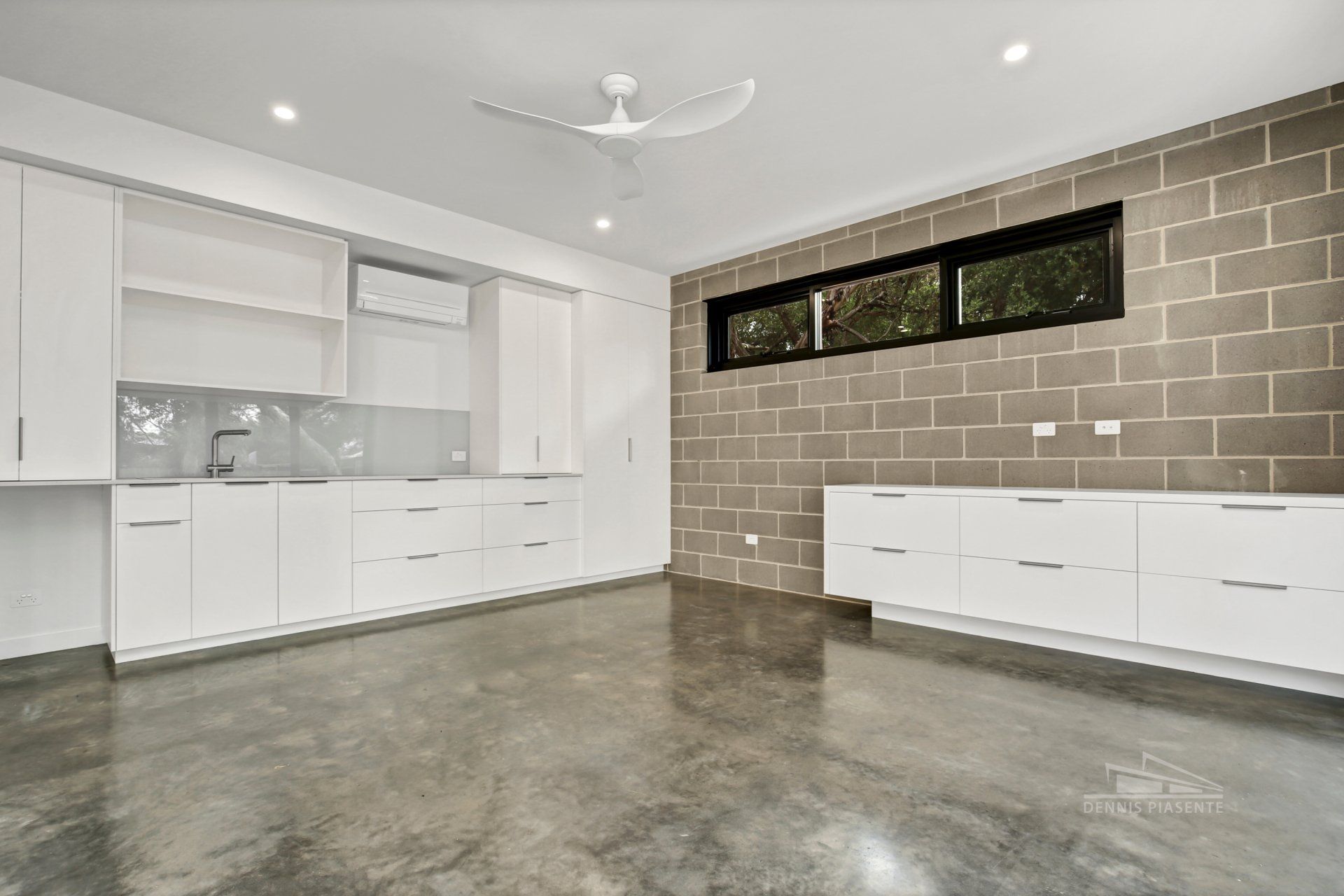 An empty kitchen with white cabinets and a ceiling fan.