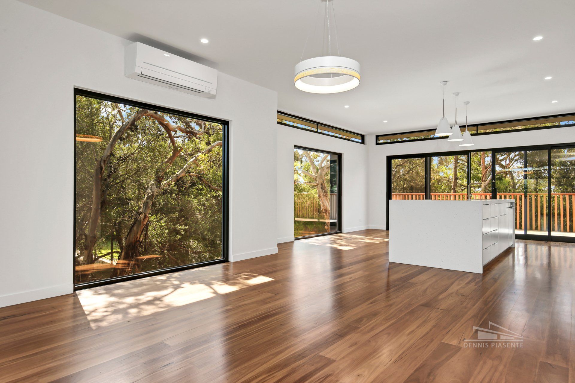 An empty living room with hardwood floors and sliding glass doors.
