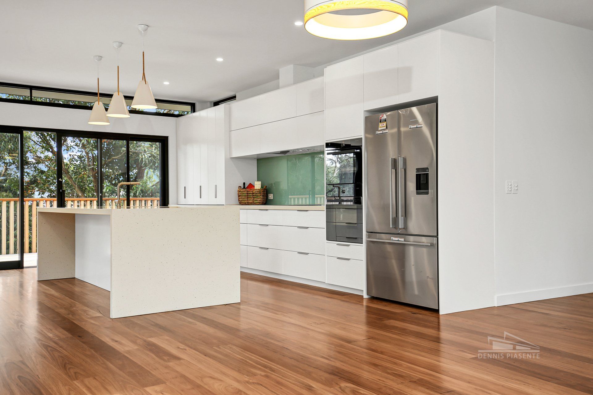 An empty kitchen with stainless steel appliances and hardwood floors.