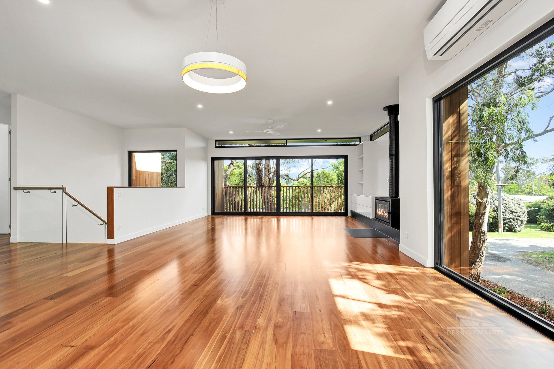 An empty living room with hardwood floors and sliding glass doors.