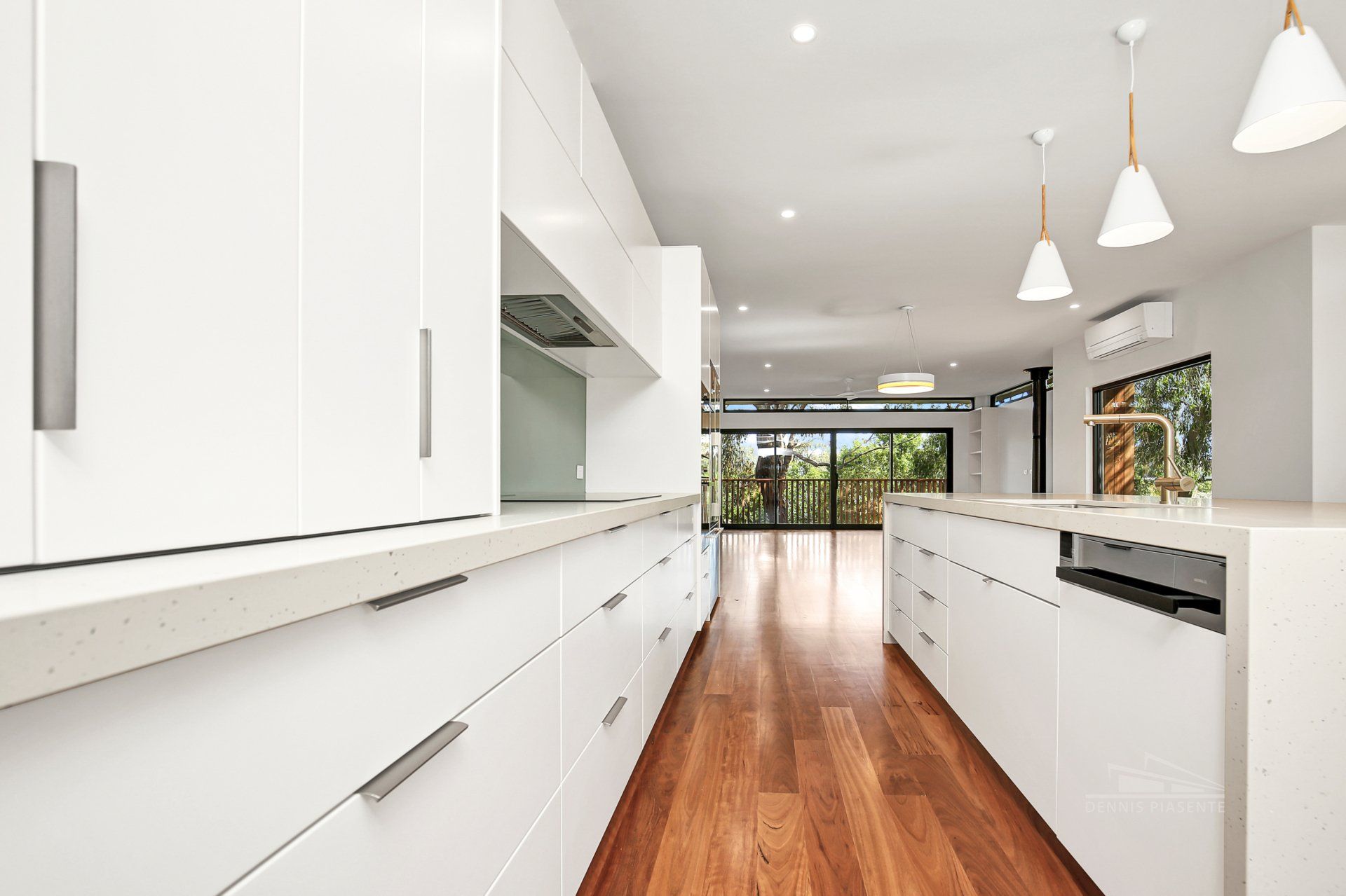 A kitchen with white cabinets and hardwood floors.