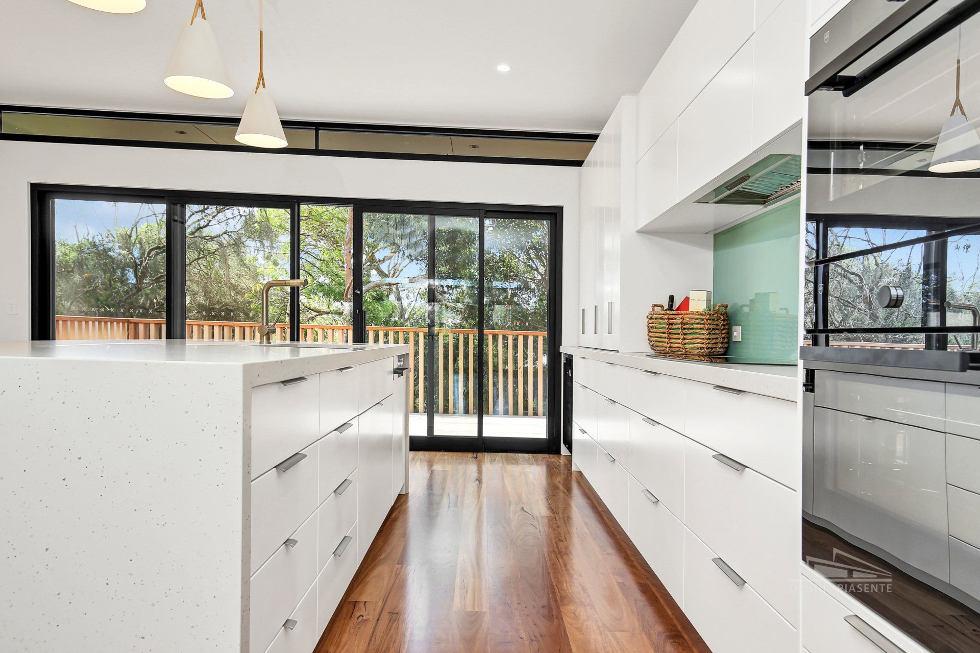 A kitchen with white cabinets and hardwood floors and a large island.