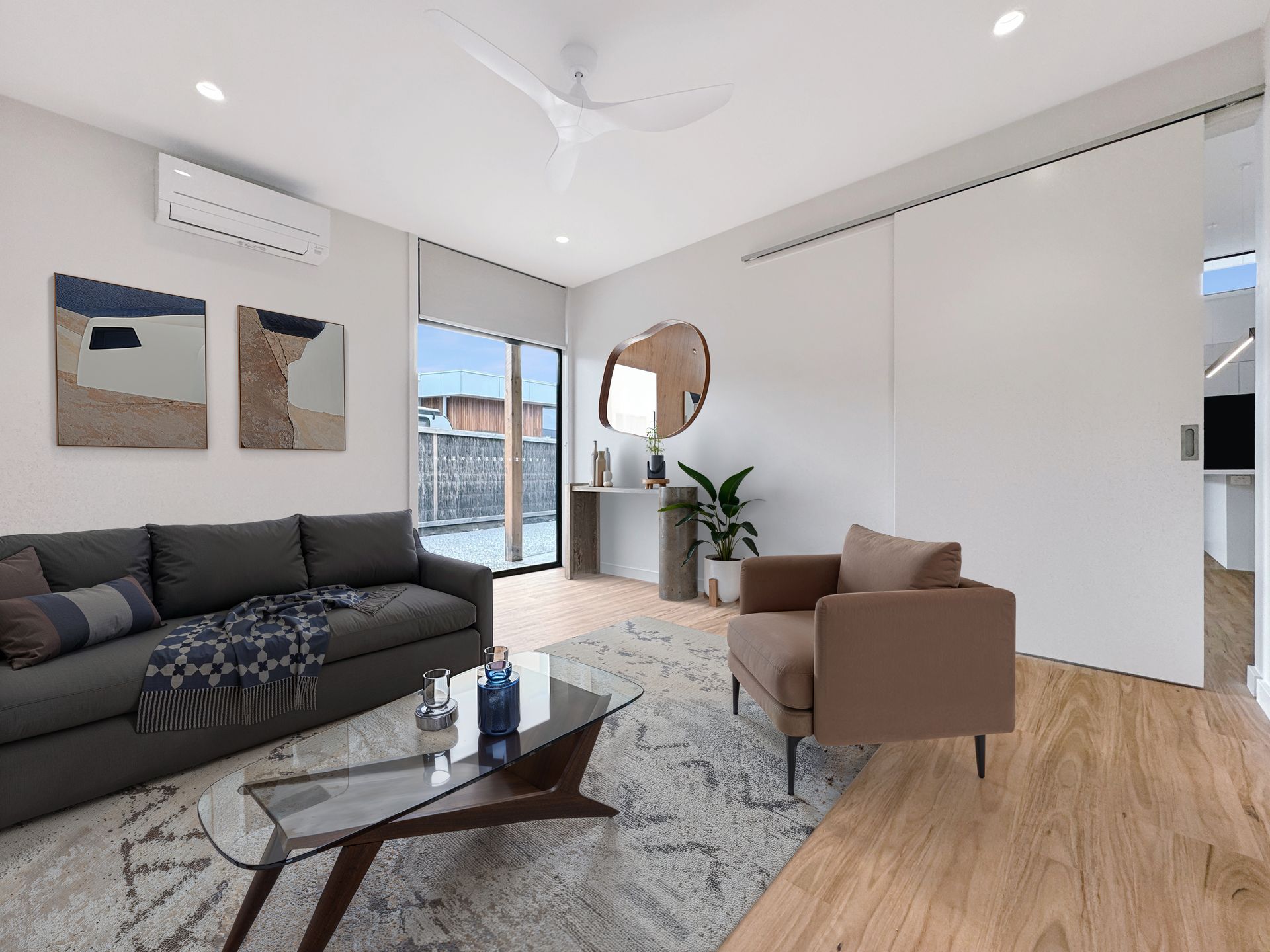 A living room with a couch , chair , coffee table and ceiling fan.